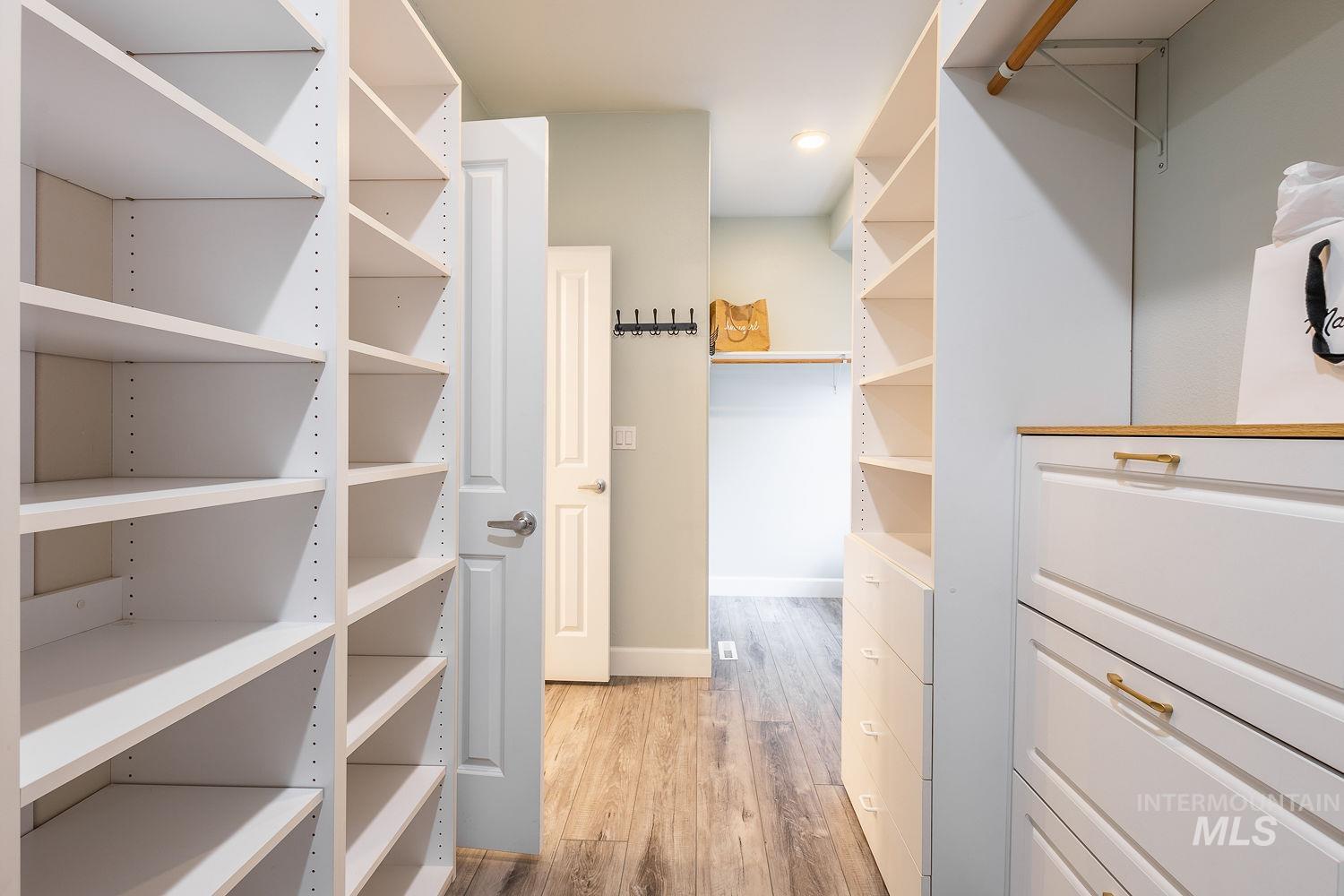 Walk in closet with light wood-style floors