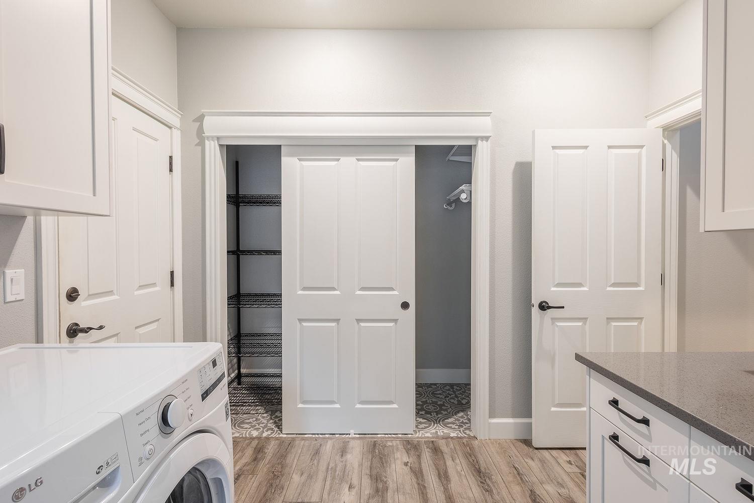 Laundry room with washer / clothes dryer, light wood-type flooring, and cabinet space