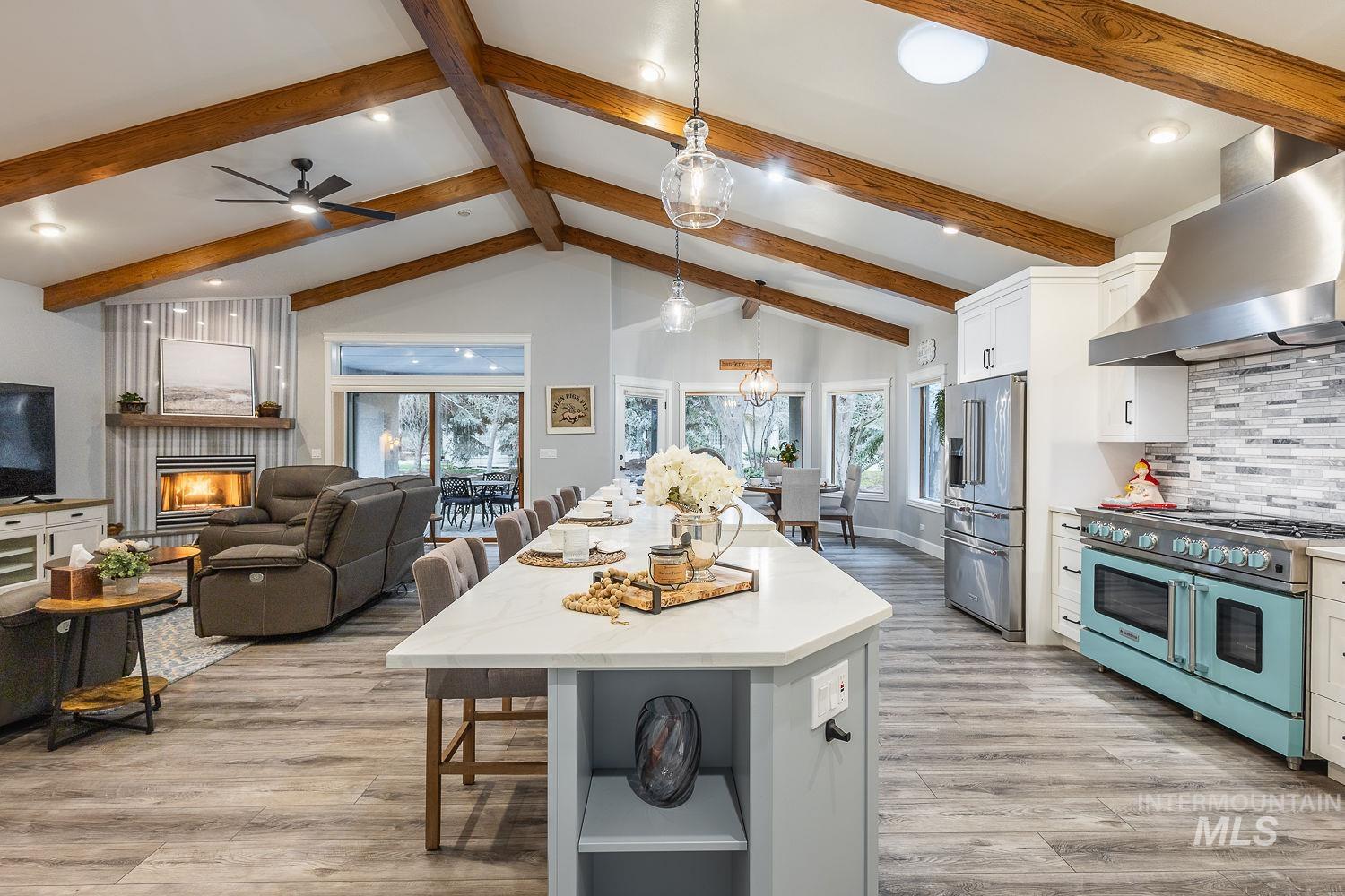Kitchen featuring a breakfast bar area, high quality appliances, a warm lit fireplace, open floor plan, and dual tone cabinets