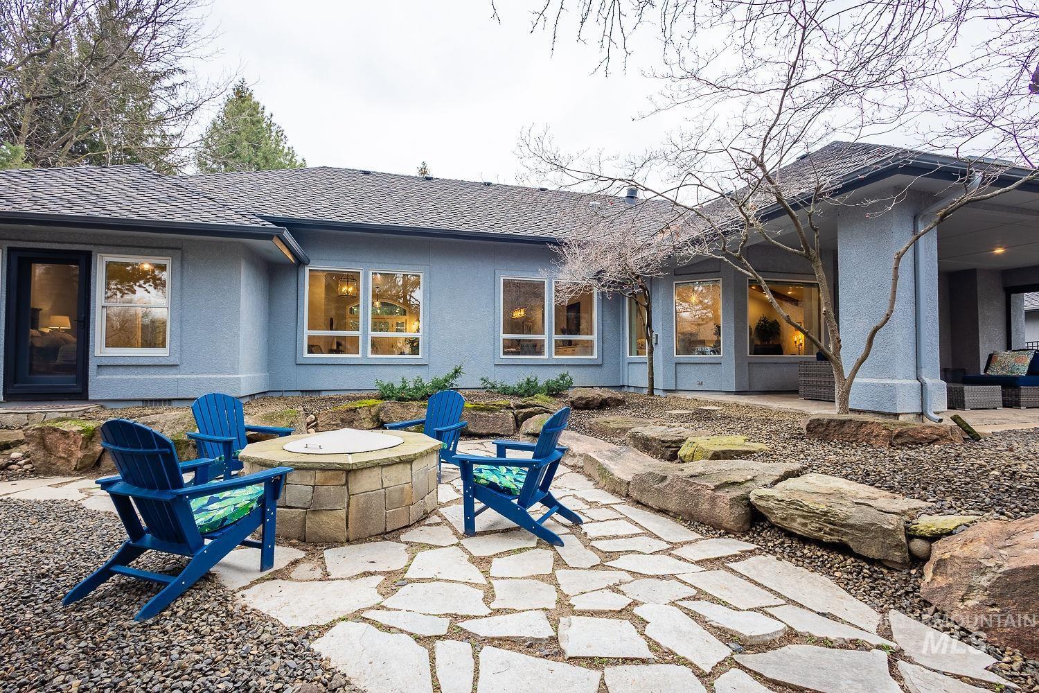 Back of house with a fire pit, a patio area, roof with shingles, and stucco siding