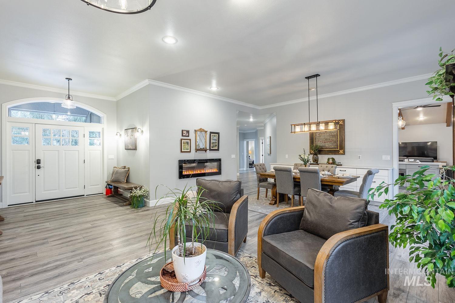Living room with ornamental molding, wood finished floors, a glass covered fireplace, and healthy amount of natural light
