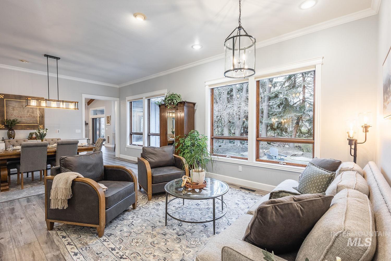 Living room featuring hanging lights, plenty of natural light, ornamental molding, and wood finished floors