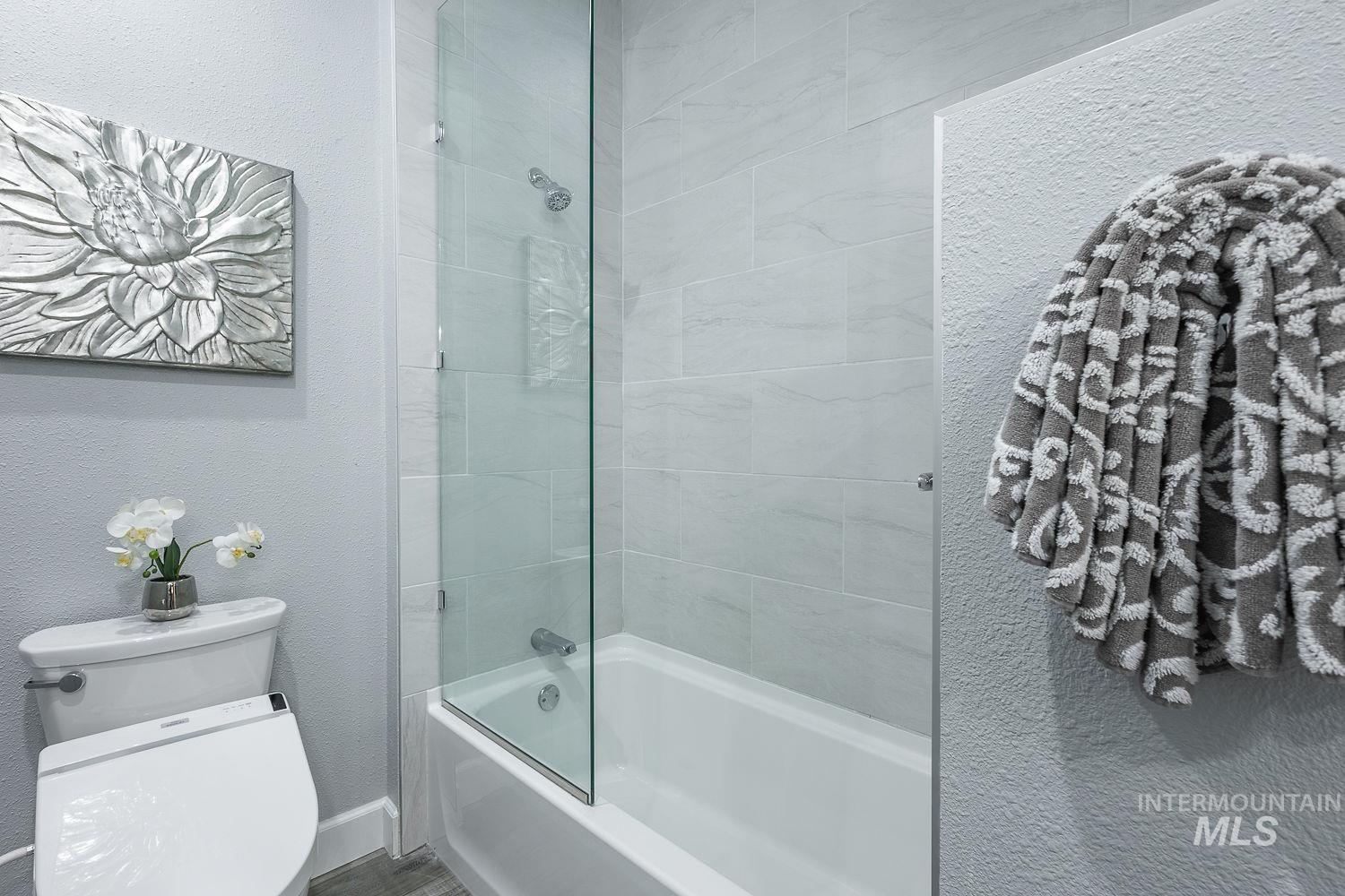 Bathroom featuring a textured wall and shower / bath combination