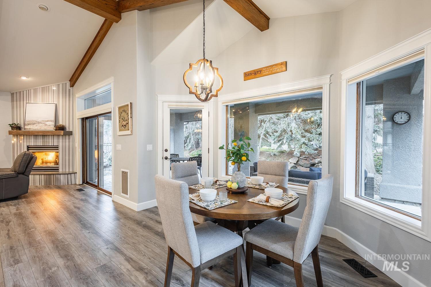 Dining area with suspended lighting, wood finished floors, and a lit fireplace