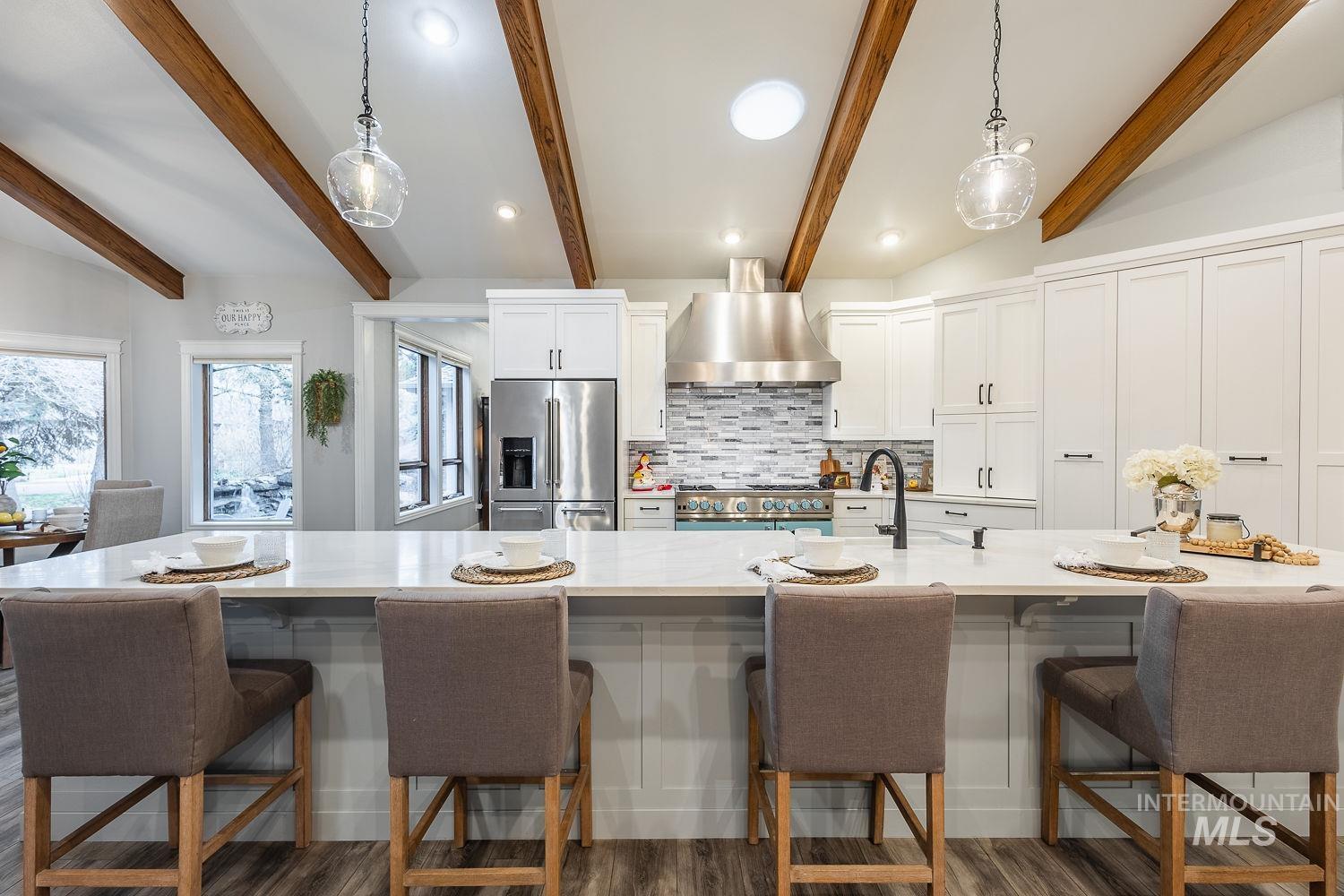 Kitchen featuring white cabinets, high quality fridge, backsplash, a breakfast bar area, and beam ceiling