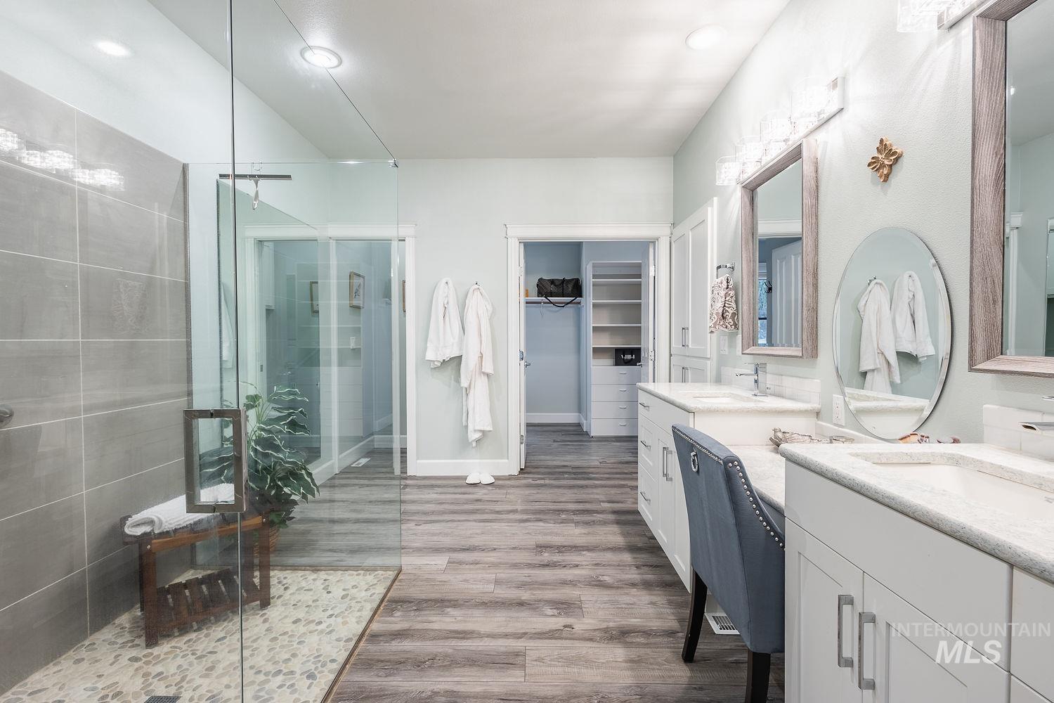 Bathroom with a shower stall, two vanities, a spacious closet, dark wood-type flooring, and recessed lighting