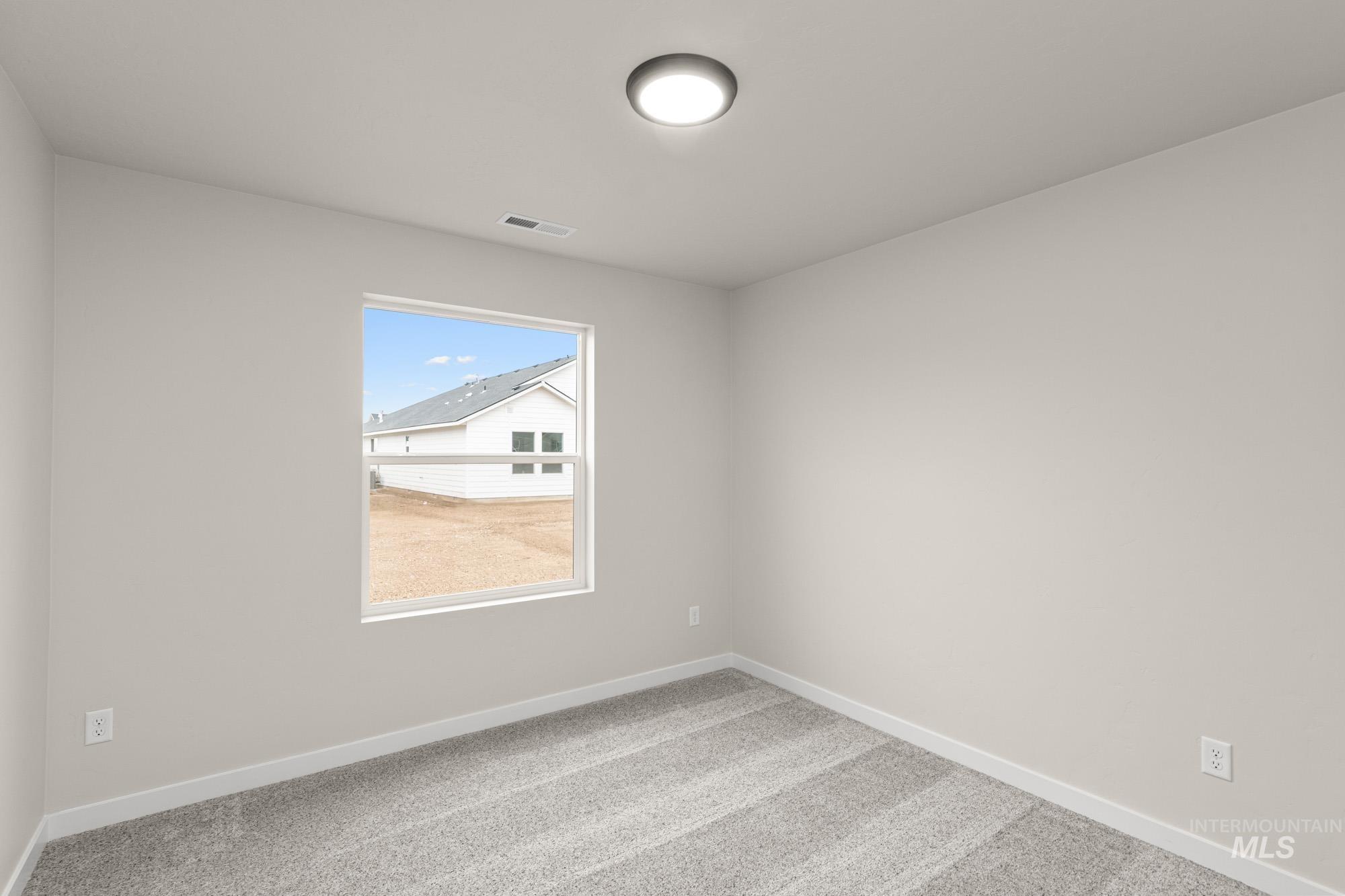 Carpeted spare room featuring baseboards