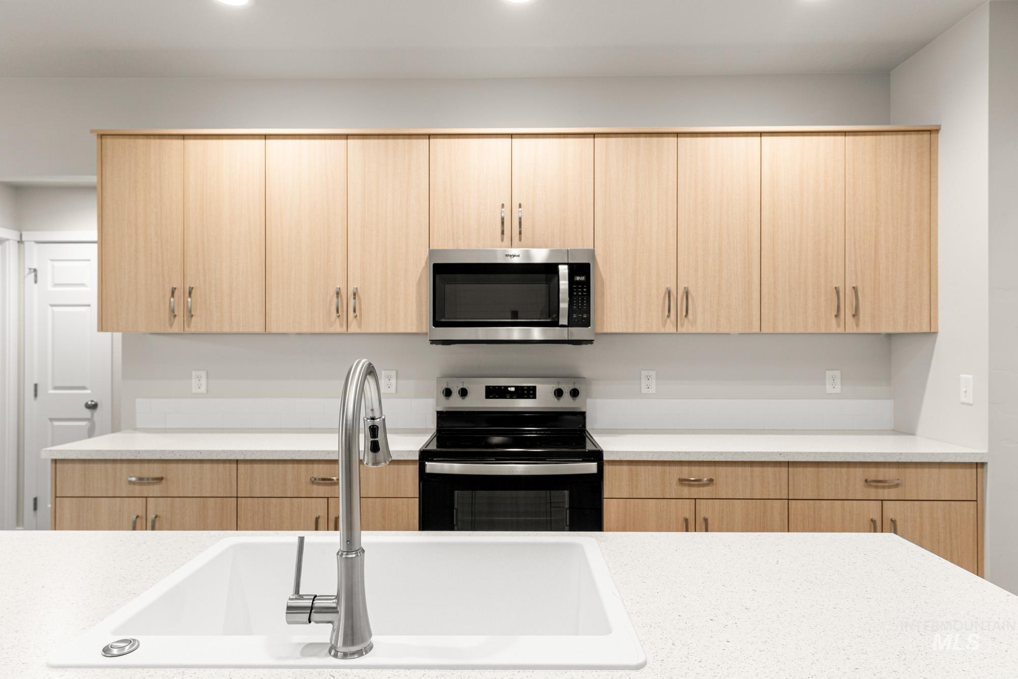 Kitchen featuring light brown cabinetry, stainless steel appliances, light stone countertops, and recessed lighting