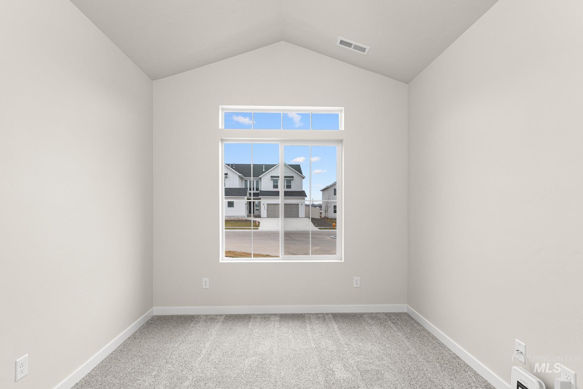 Empty room with light colored carpet and lofted ceiling