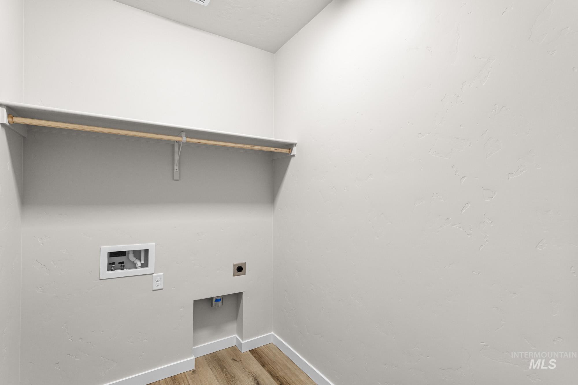 Washroom with light wood-style flooring, hookup for an electric dryer, and washer hookup