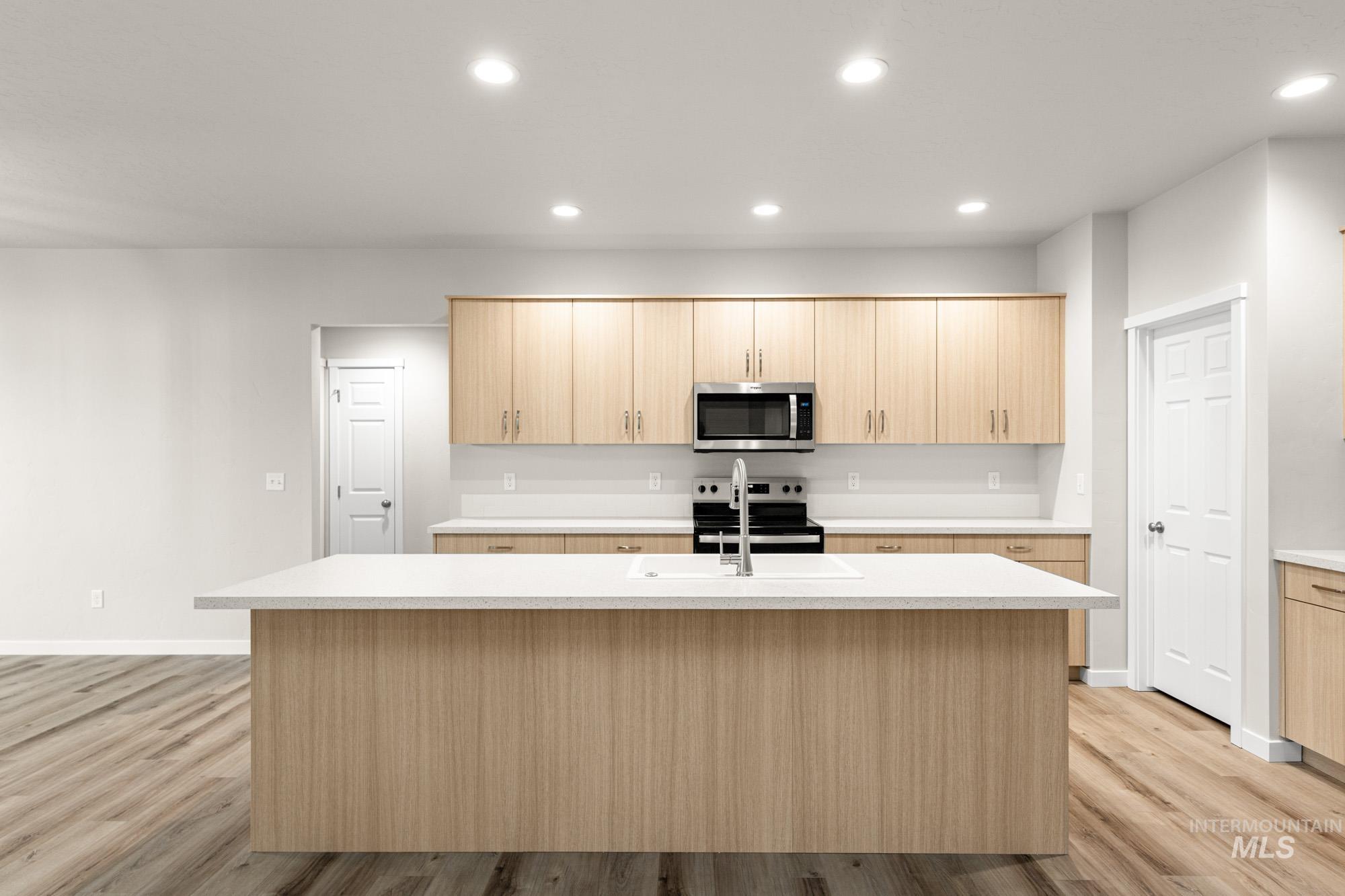 Kitchen featuring light brown cabinetry, an island with sink, stainless steel appliances, and recessed lighting
