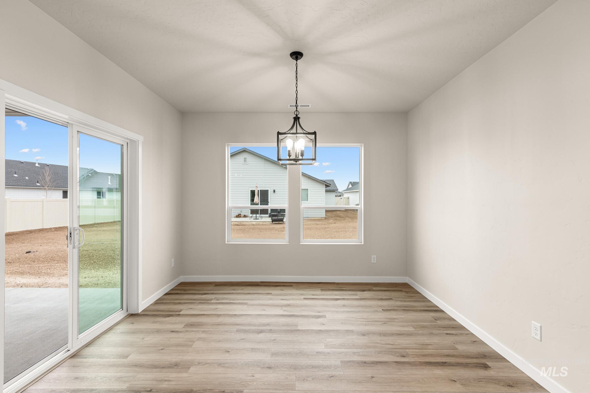 Unfurnished dining area featuring a chandelier and light wood-style floors