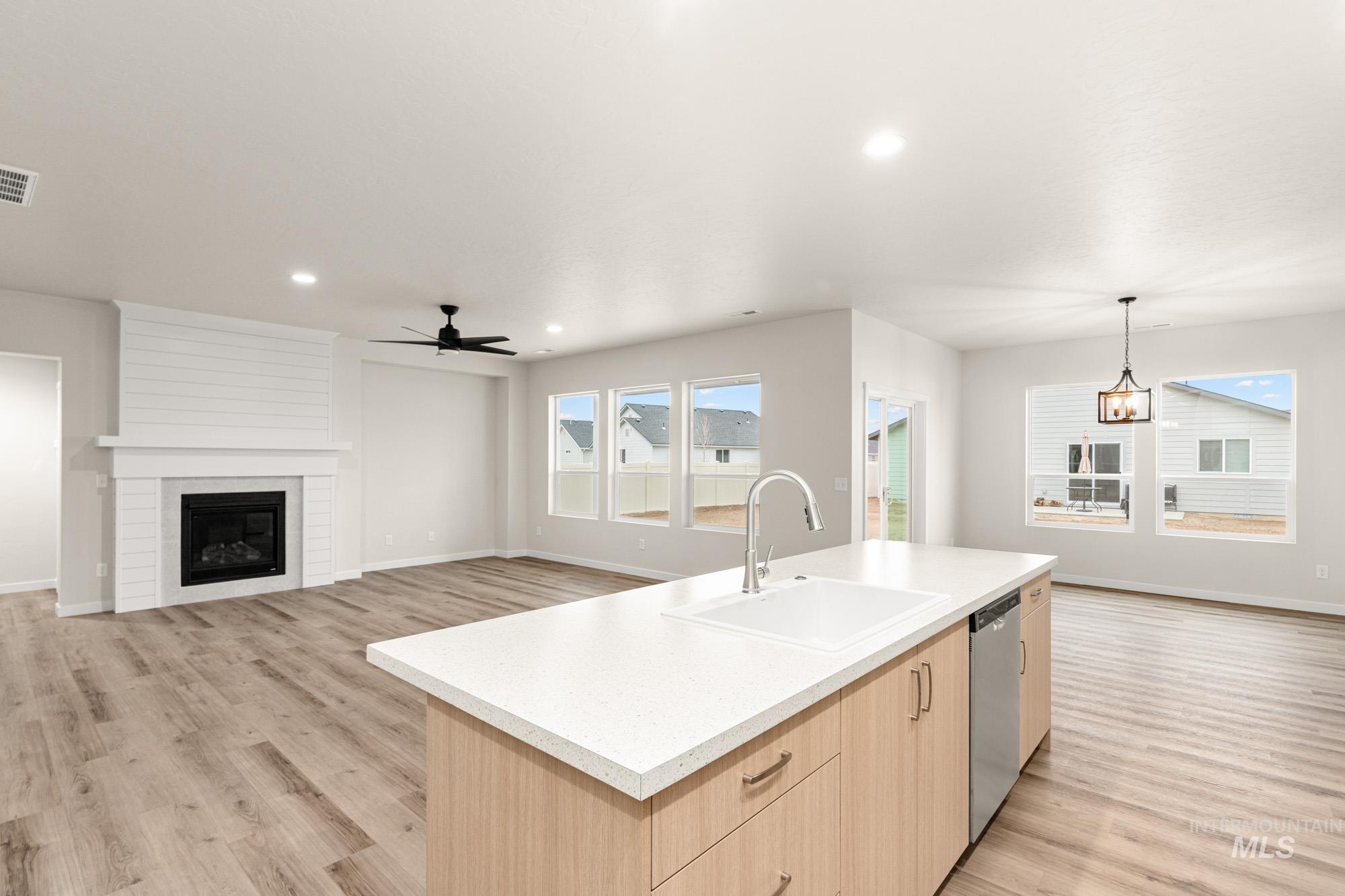 Kitchen with light brown cabinets, open floor plan, light wood finished floors, a fireplace, and recessed lighting