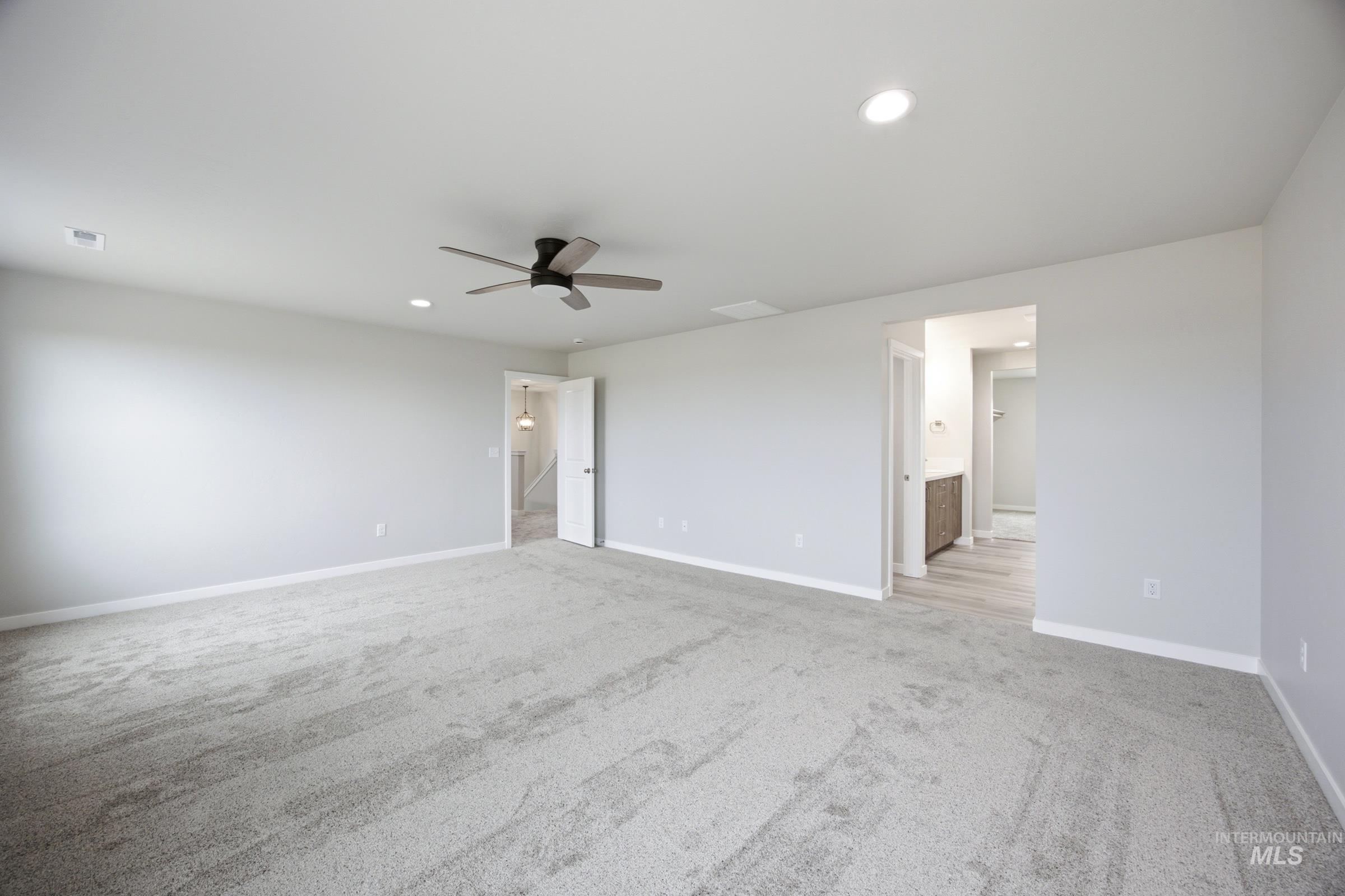 Spacious room featuring light gray carpeting, recessed lighting, a ceiling fan, and white trim
