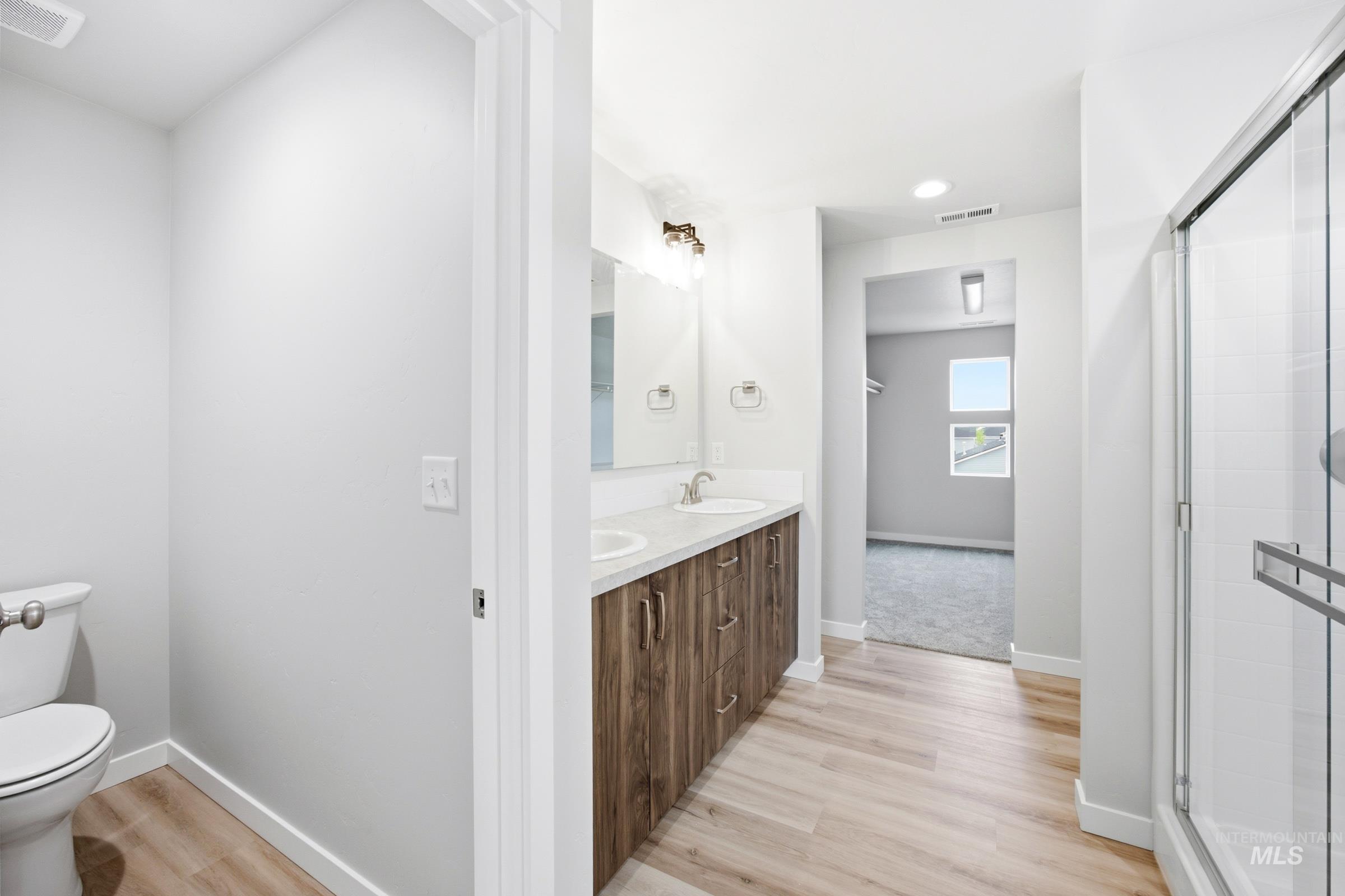 Bathroom featuring a dual vanity with wood-finish cabinetry, light countertops, and individual sinks