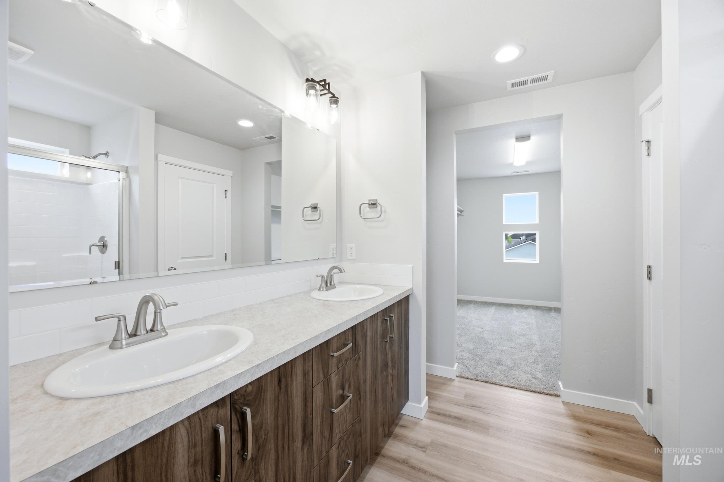 Dual vanity featuring wood-finish cabinetry and light-toned countertops