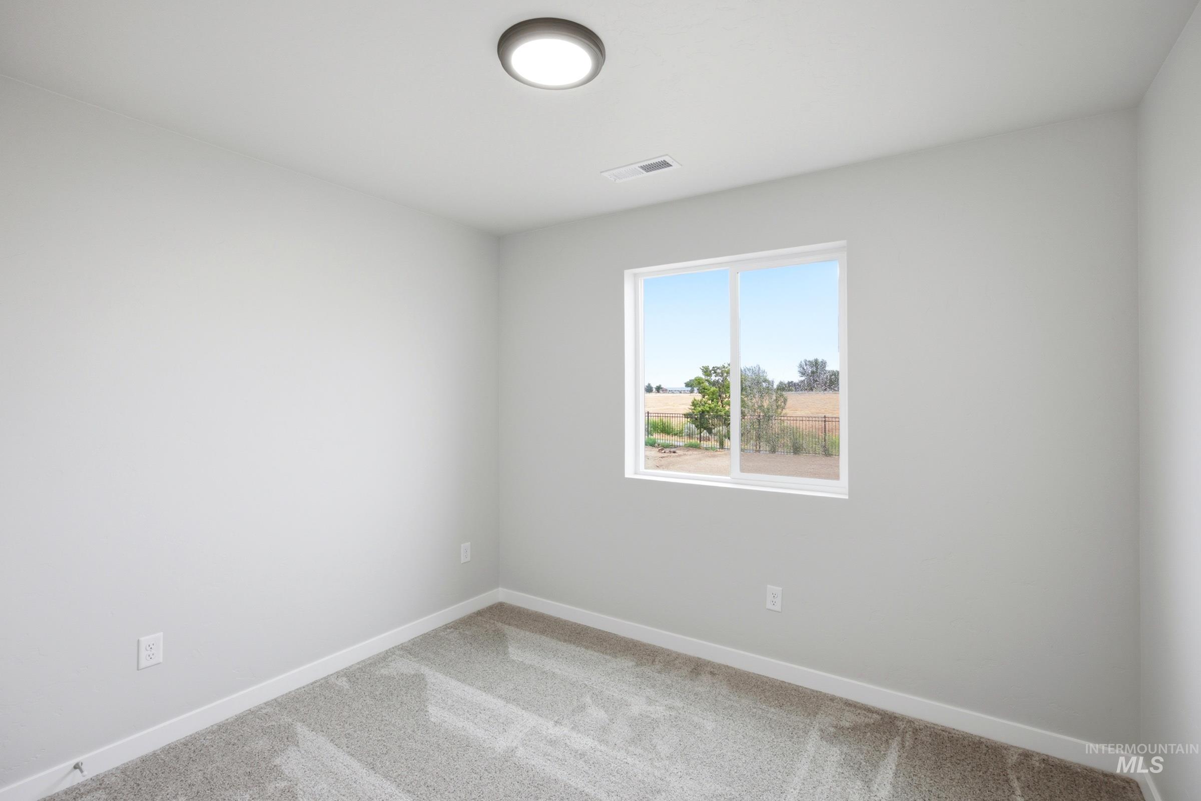 Bright room featuring a picture window, neutral wall paint, carpet flooring, a flush-mount ceiling light, and white baseboards