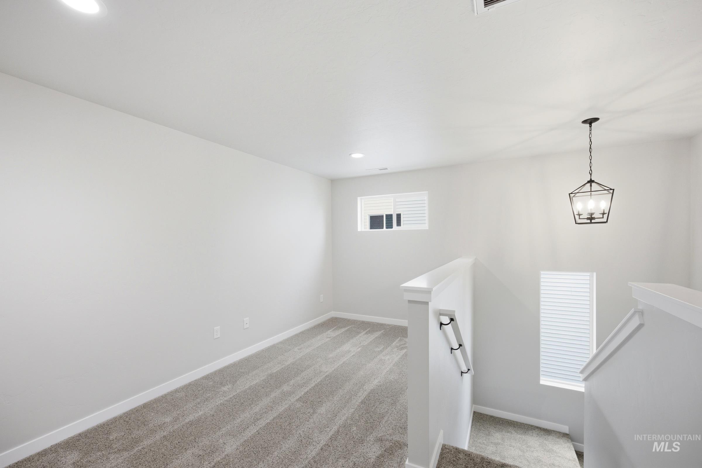 Loft area featuring neutral carpeting and a contemporary geometric chandelier