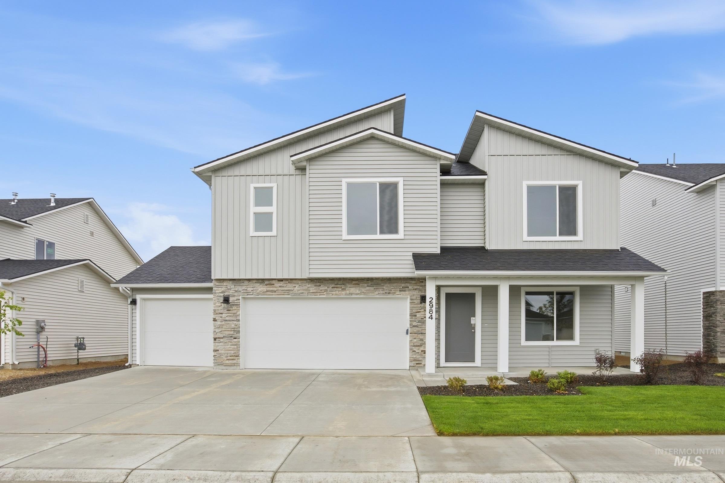 Modern two-story residence featuring light gray siding and stone veneer accents