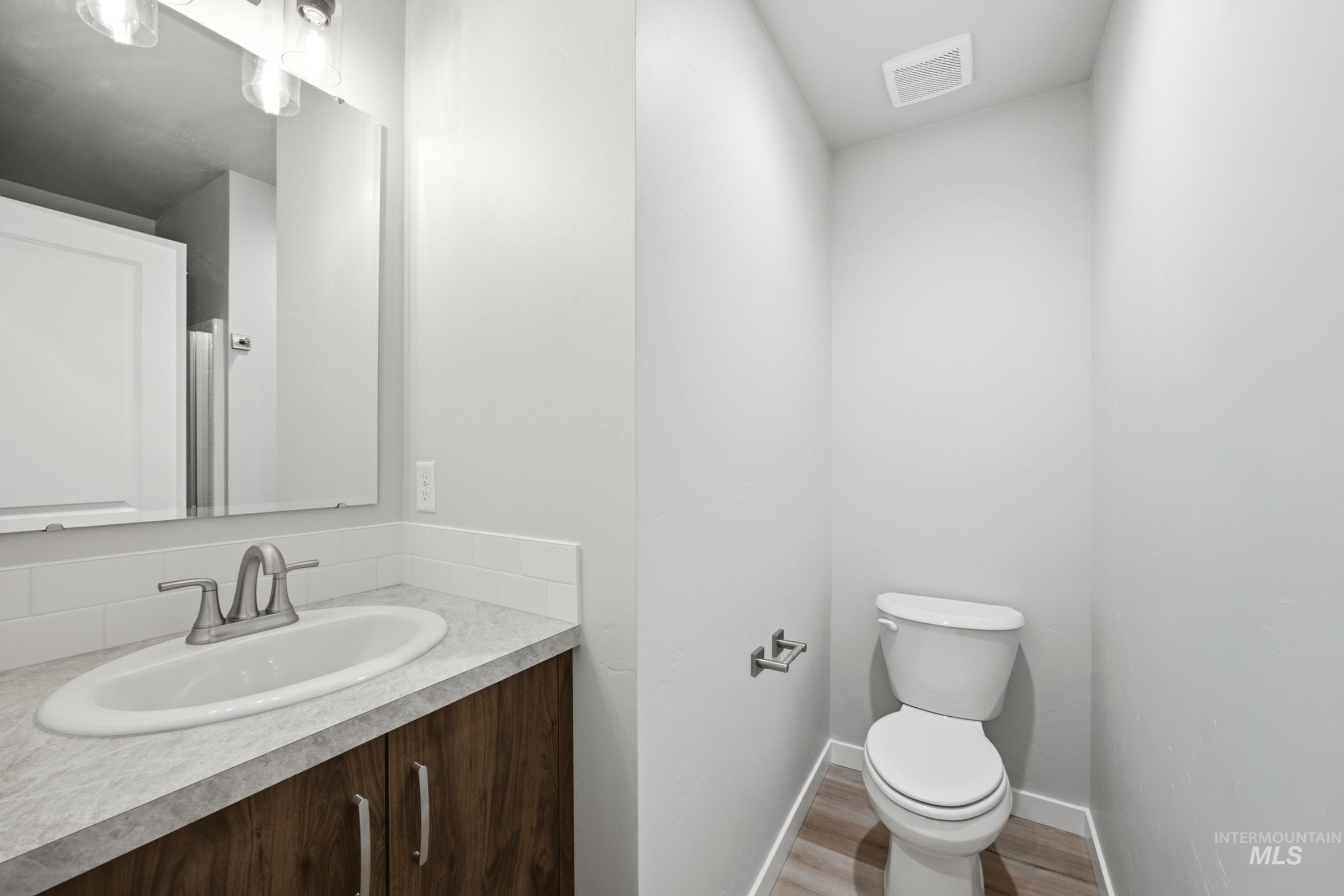 Bathroom featuring a wood-finish vanity with a light-toned countertop, oval undermount sink, and brushed nickel faucet
