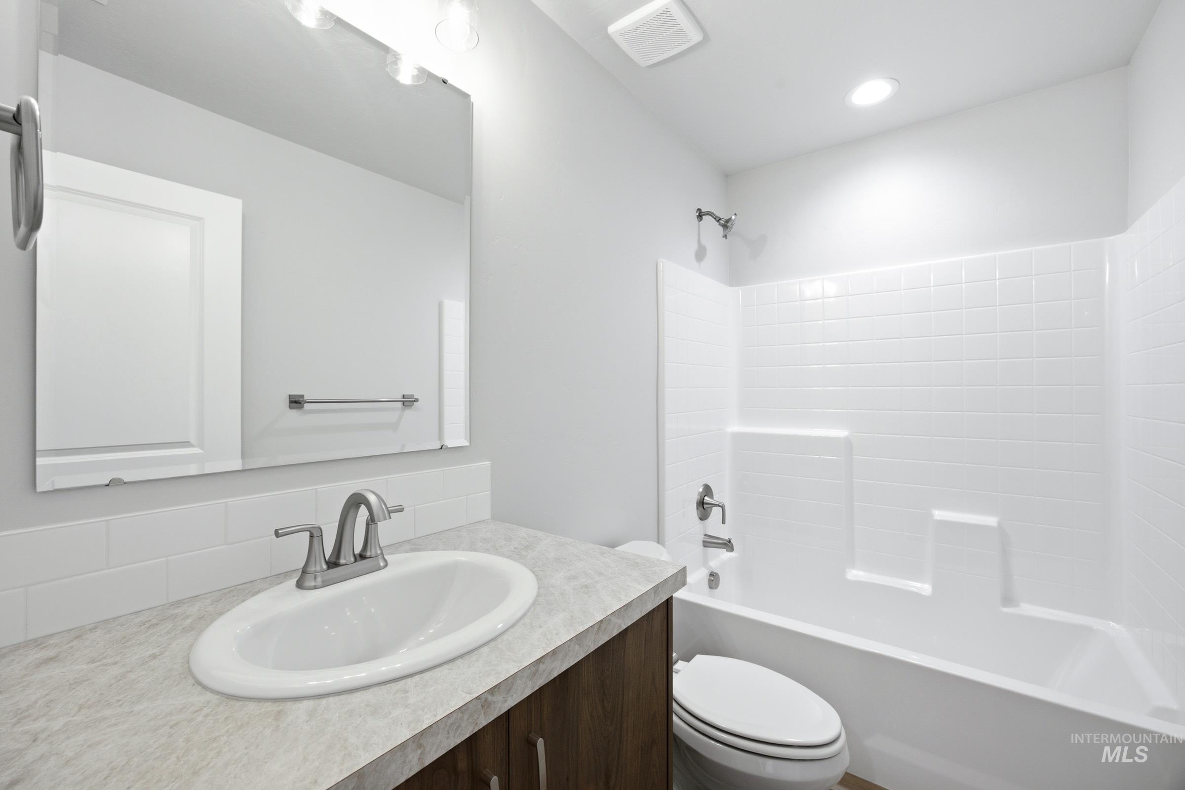 Full bathroom featuring a single vanity with a white oval sink, brushed nickel faucet, and neutral countertop