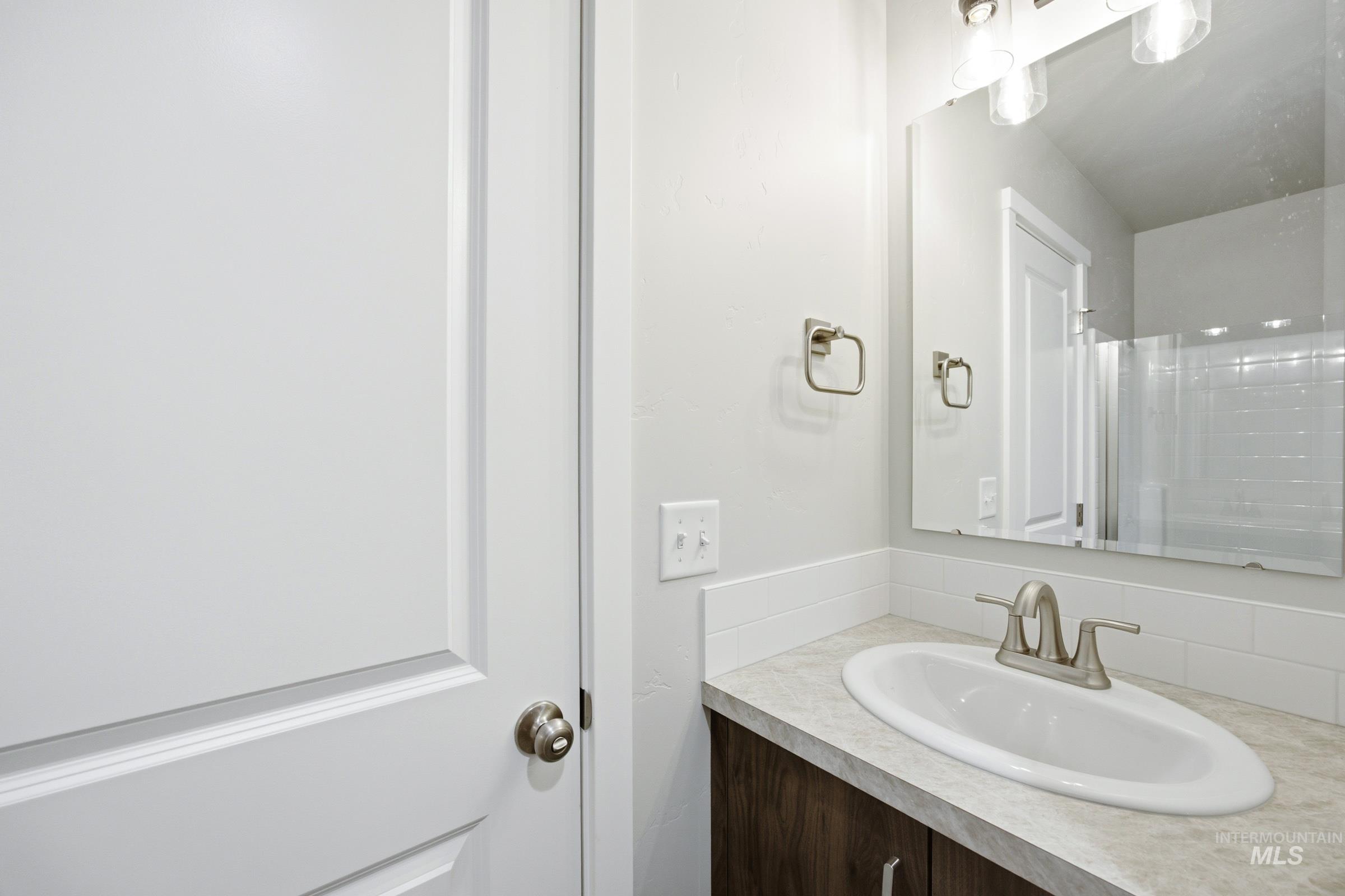 Single vanity with a white oval sink, brushed nickel faucet, and a light-toned countertop