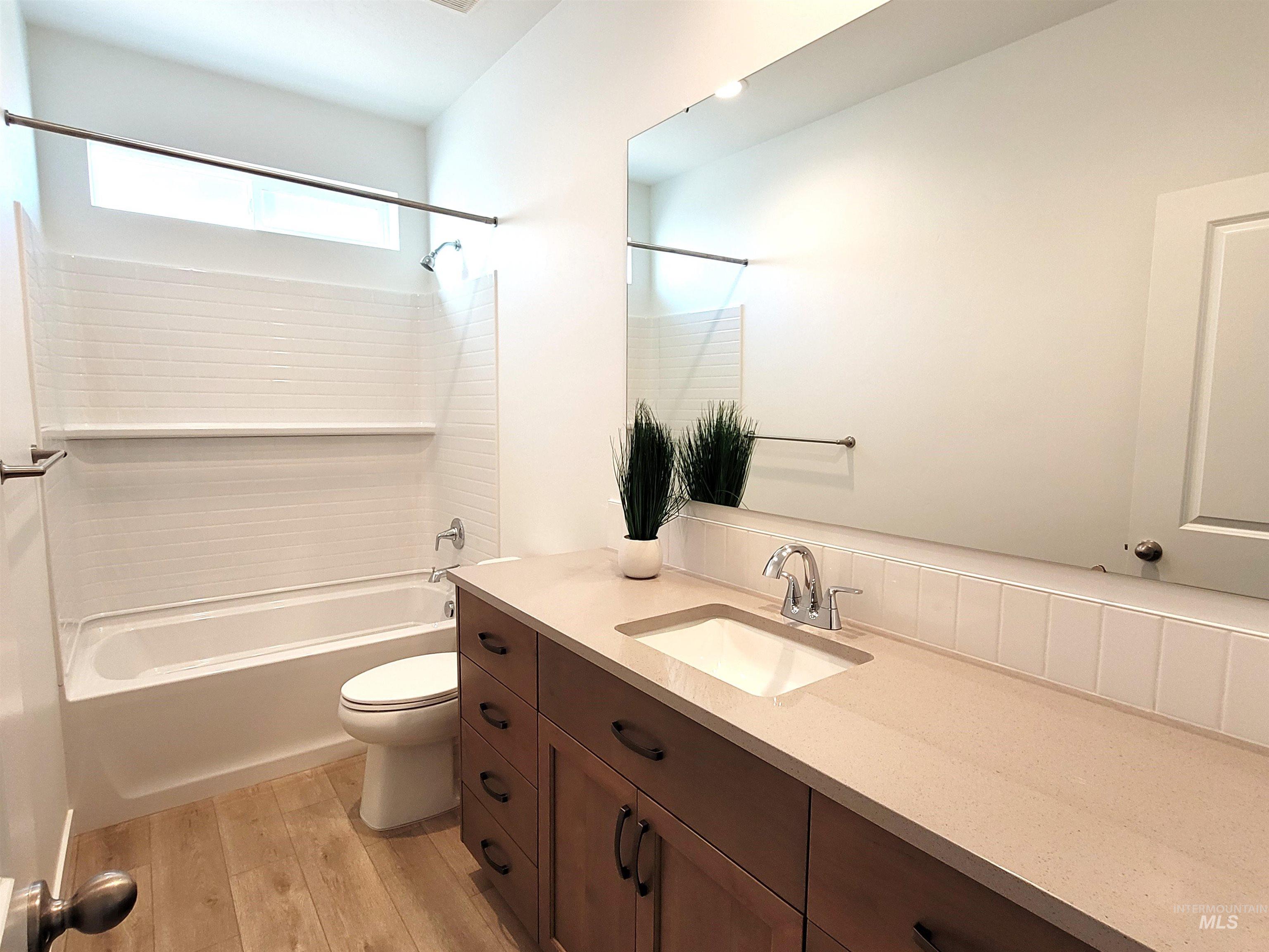 Bathroom with tub / shower combination, light wood-type flooring, and vanity