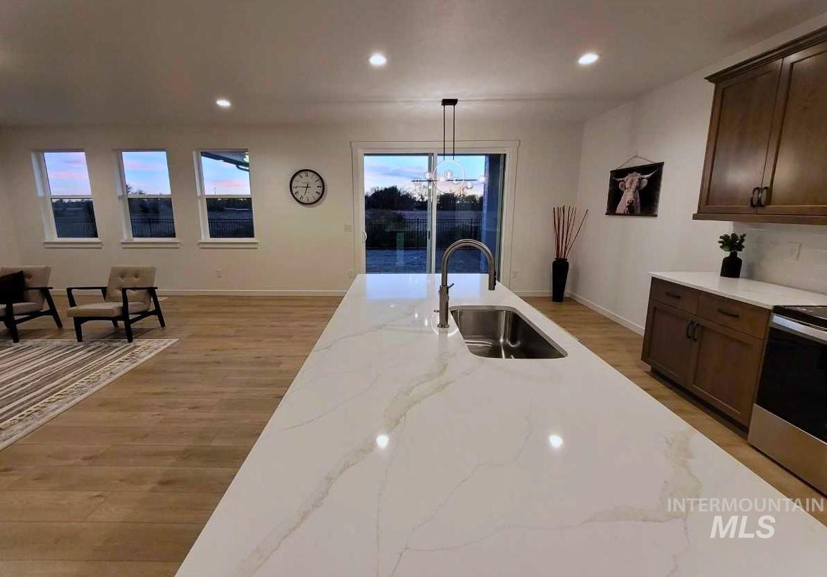 Kitchen featuring dark brown cabinetry, recessed lighting, light stone counters, stainless steel electric range, and light wood-type flooring