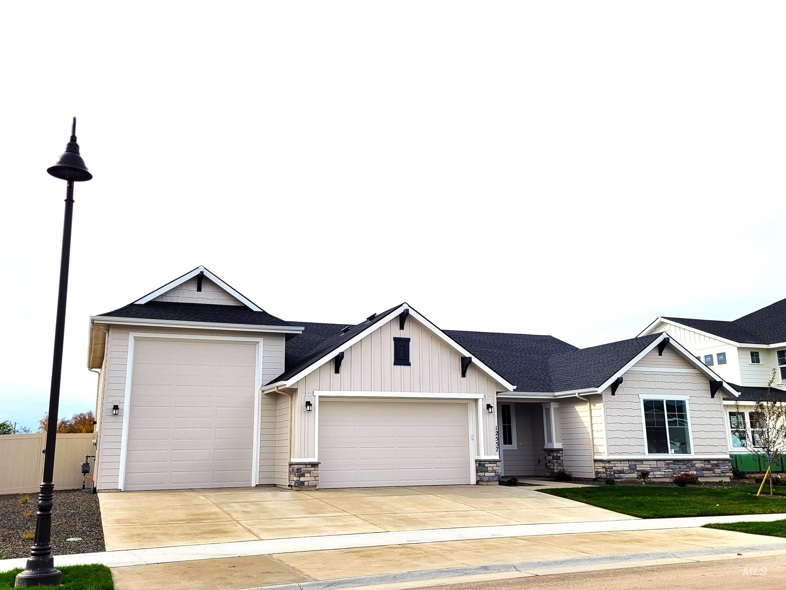 View of front of property with board and batten siding, concrete driveway, an attached garage, a shingled roof, and stone siding