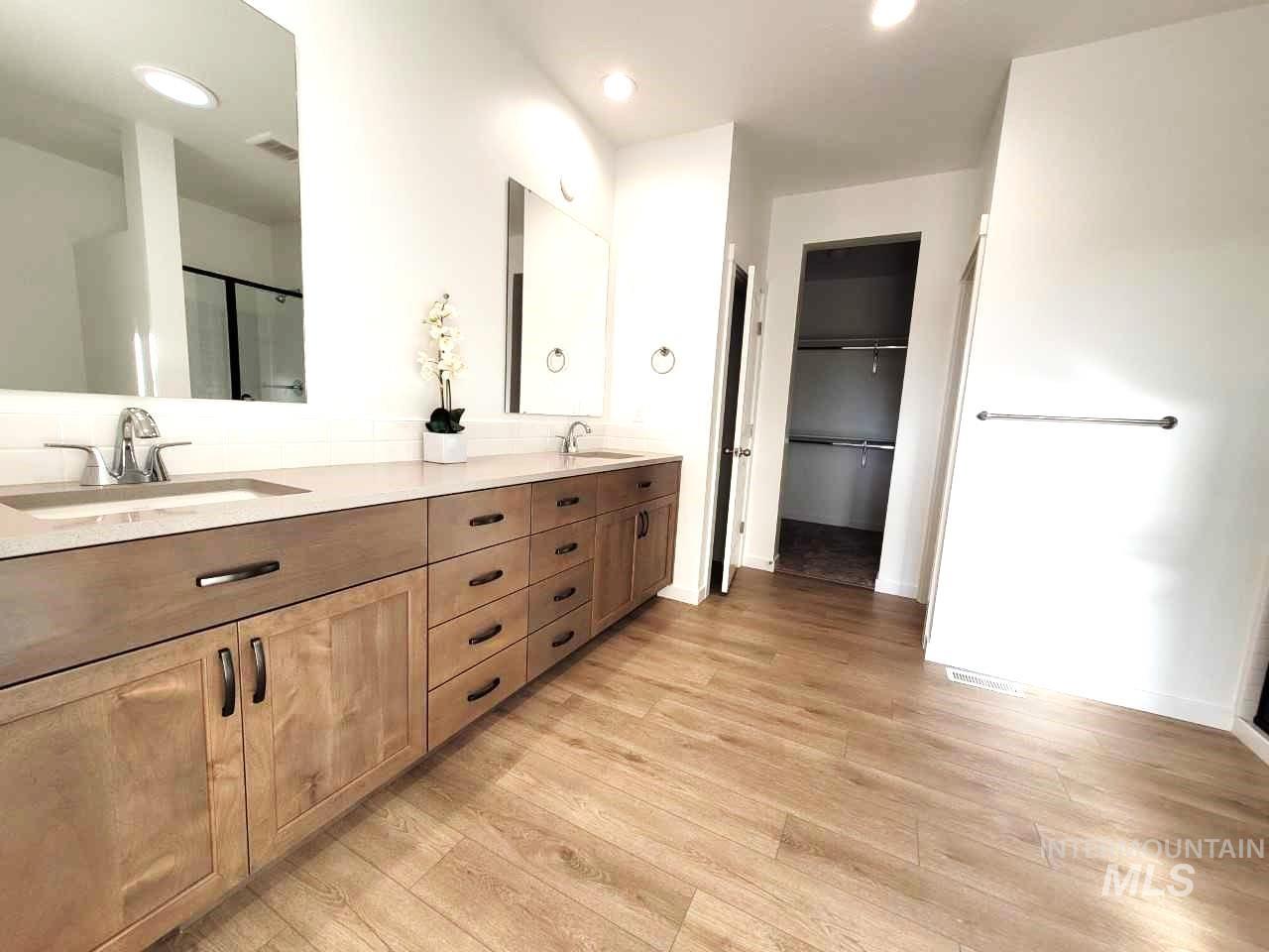 Full bathroom featuring double vanity, a stall shower, light wood-style floors, a walk in closet, and recessed lighting