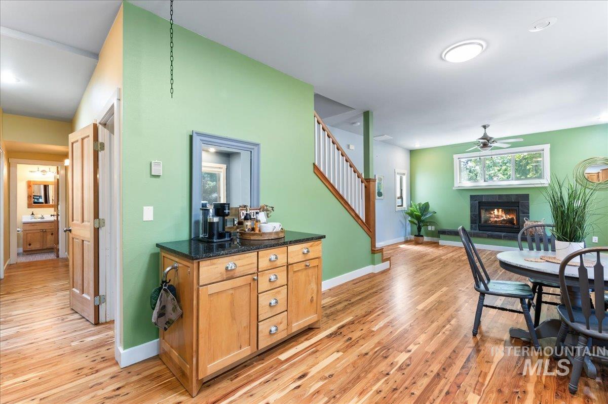 Dining space featuring a tile fireplace, a ceiling fan, light wood-style flooring, and stairs