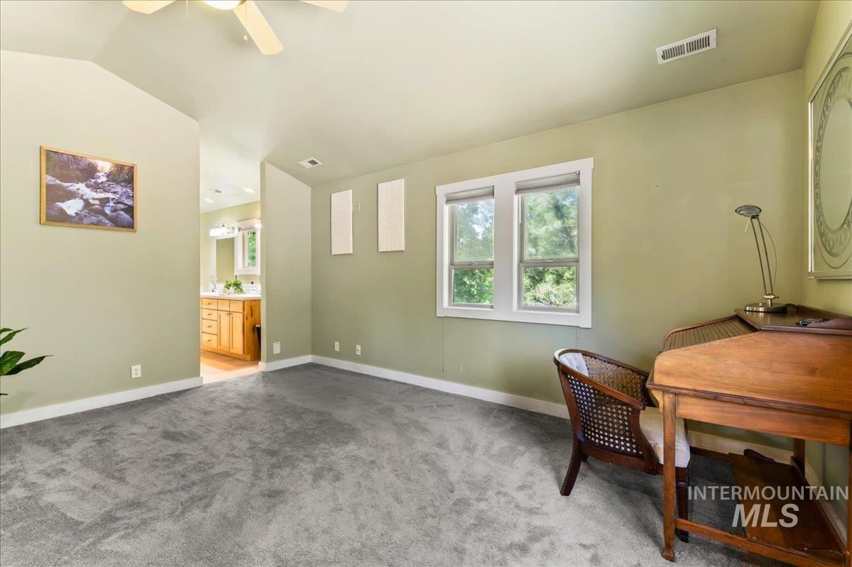 Carpeted office space with vaulted ceiling and ceiling fan