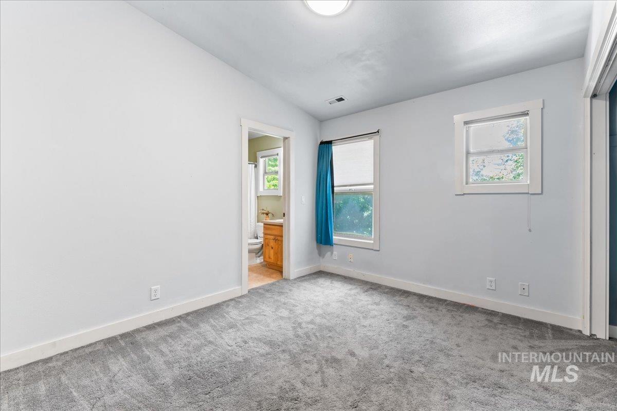 Carpeted empty room featuring vaulted ceiling and baseboards