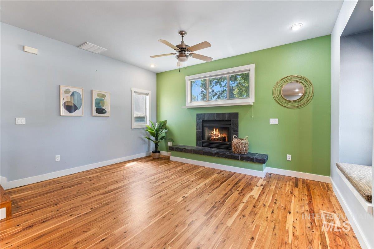 Unfurnished living room featuring wood finished floors, a fireplace, a ceiling fan, and recessed lighting