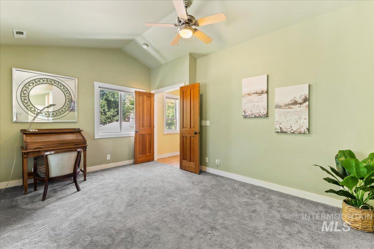 Living area with carpet floors, lofted ceiling, and ceiling fan
