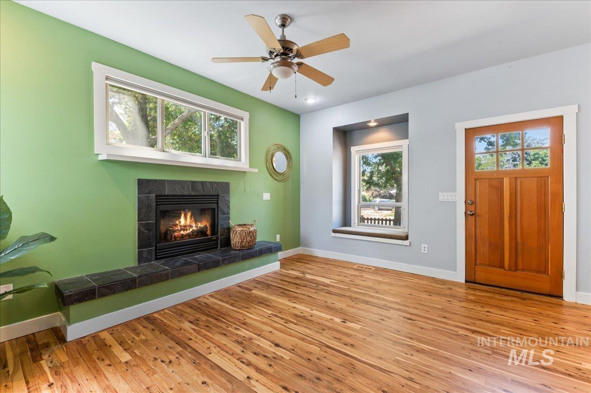 Living area with hardwood / wood-style flooring, a fireplace, and a ceiling fan