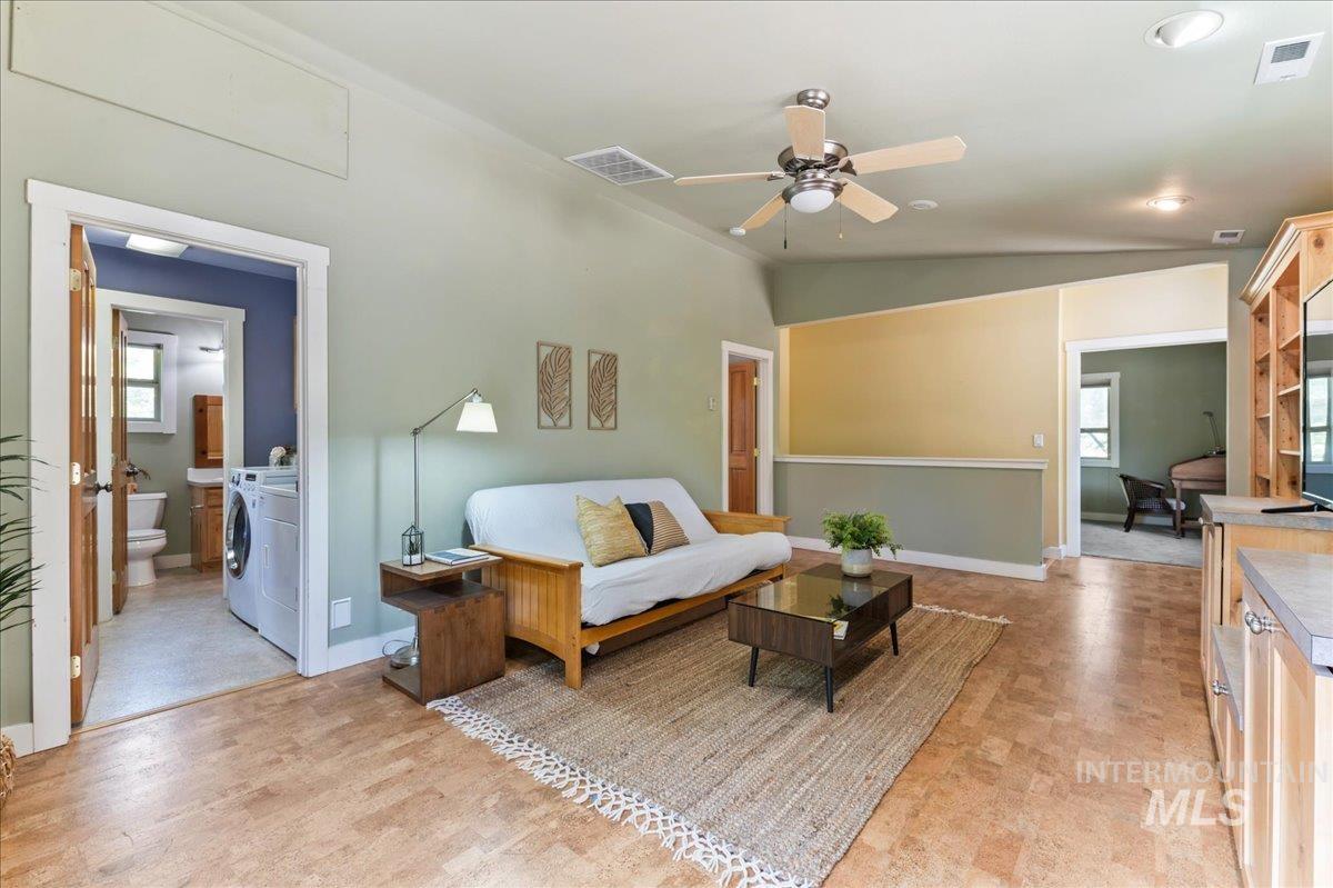 Living room with healthy amount of natural light, ceiling fan, lofted ceiling, and washing machine and dryer