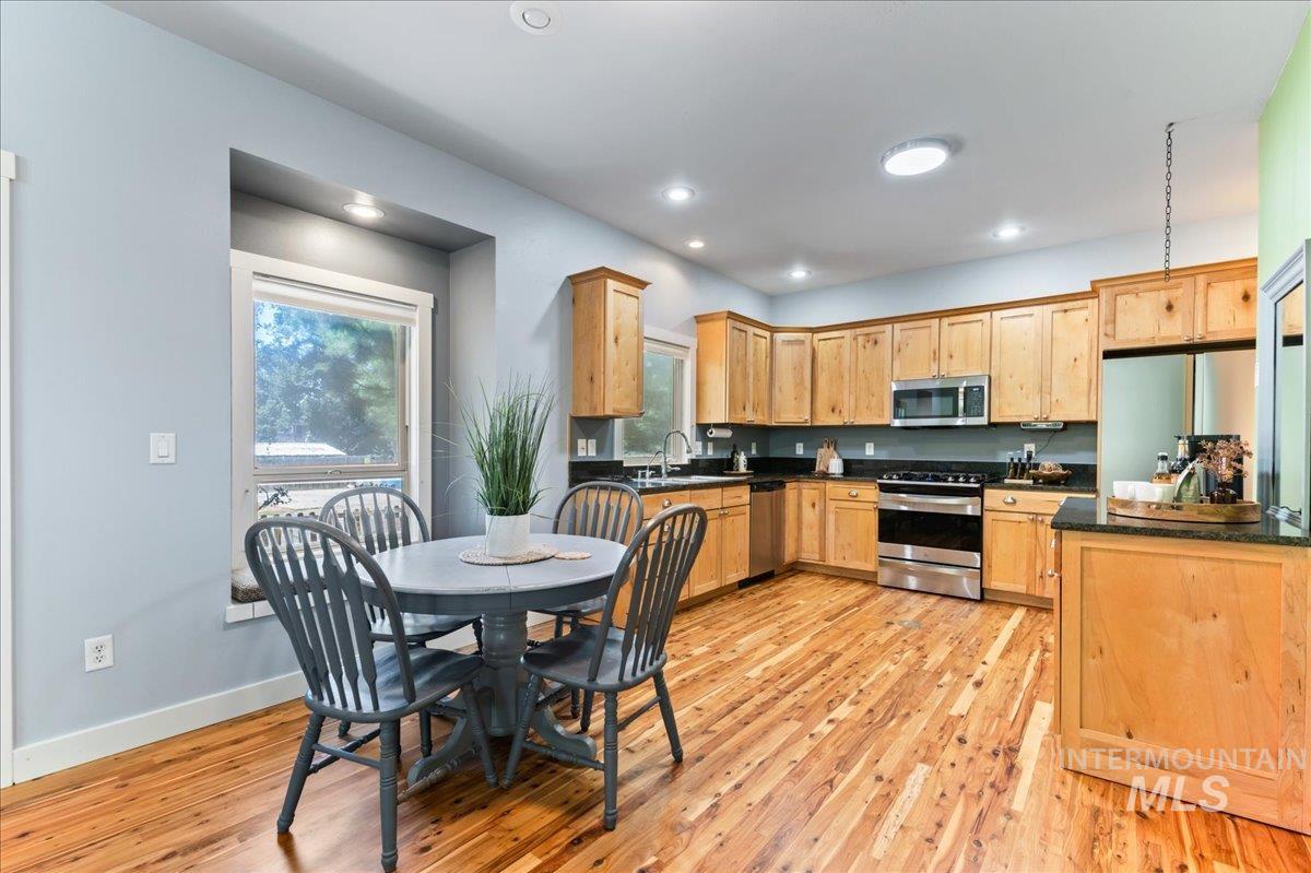 Kitchen featuring stainless steel appliances, dark countertops, light wood finished floors, recessed lighting, and light brown cabinetry