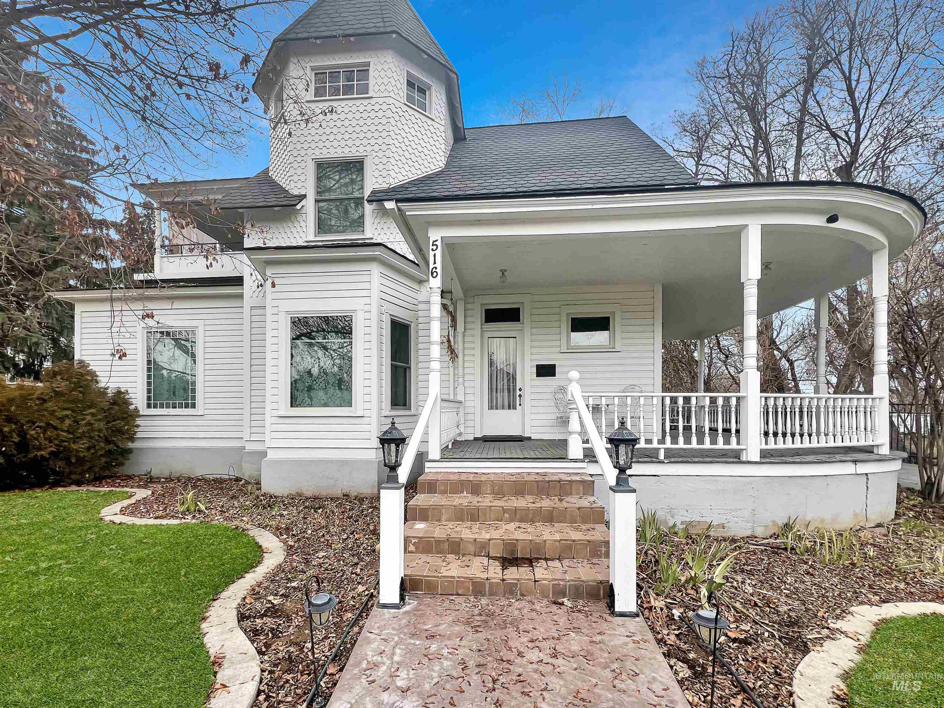 Victorian house featuring covered porch, a shingled roof, and a front lawn