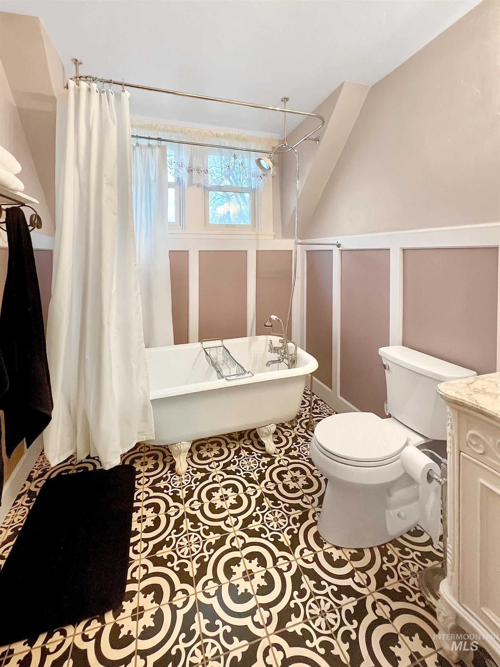 Full bath featuring vanity, a combined bath / shower with freestanding tub, a decorative wall, and tile patterned floors
