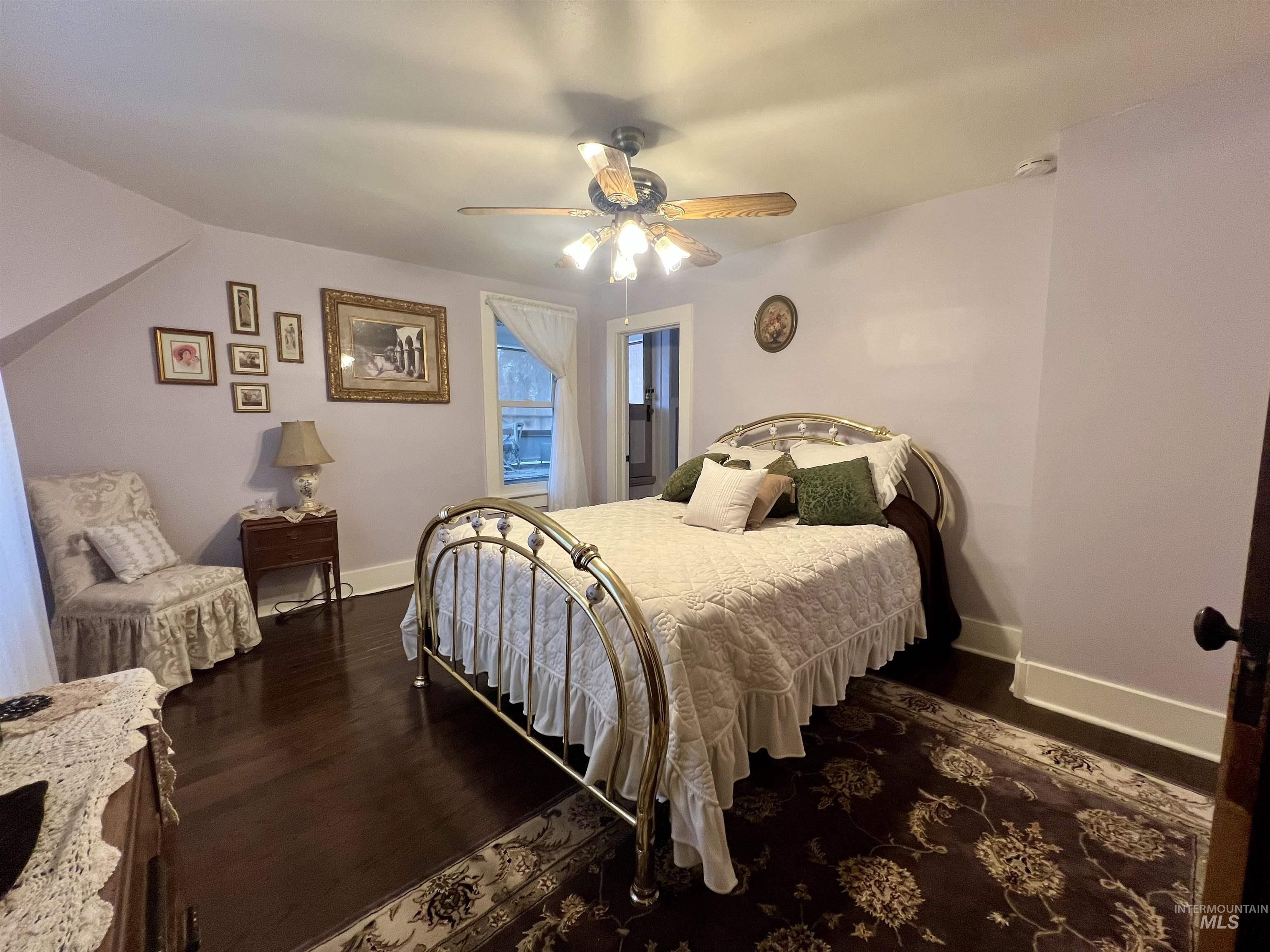 Upstairs bedroom featuring a ceiling fan and dark wood-style floors