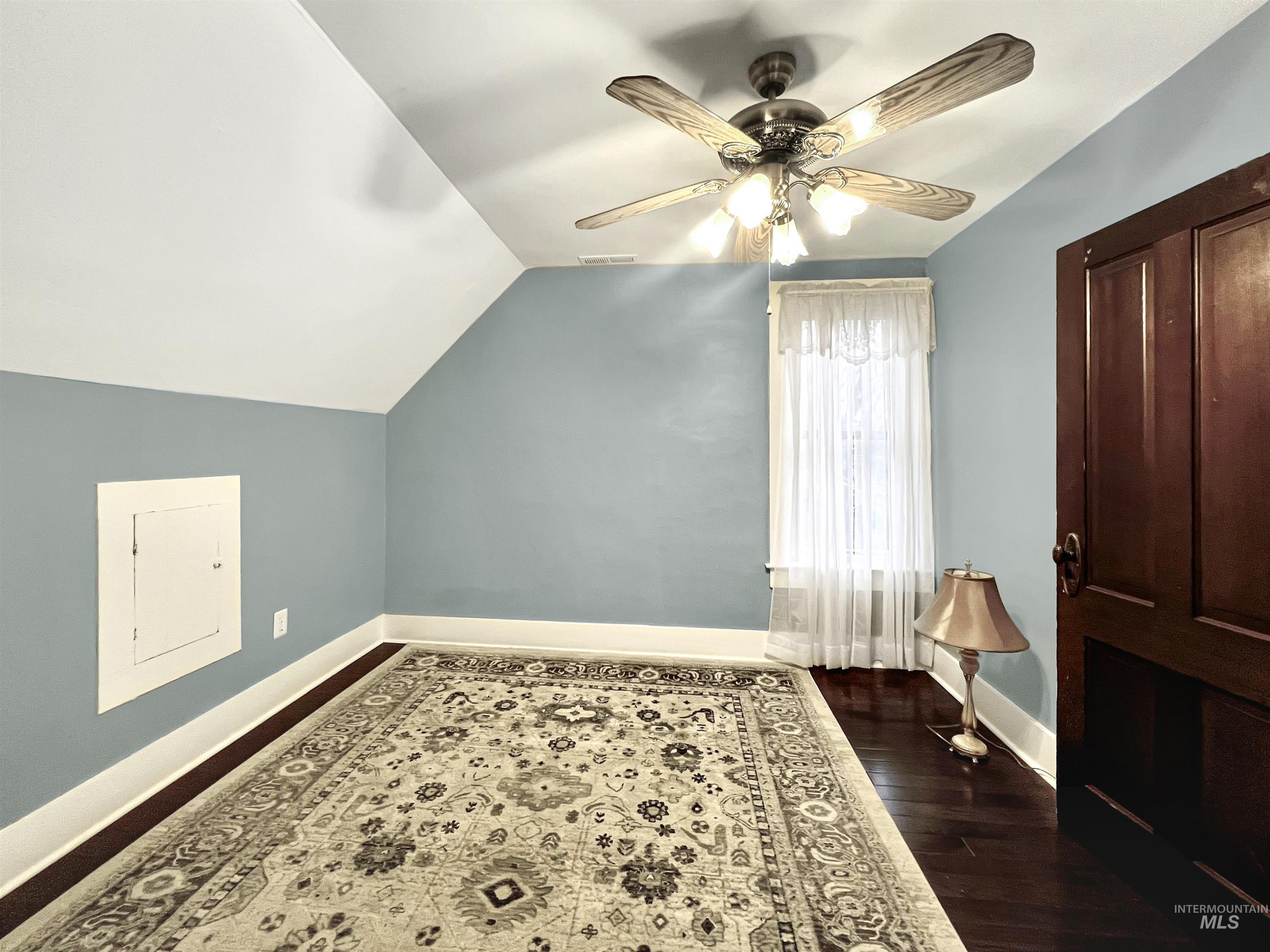 Additional upstairs bedroom with a ceiling fan, vaulted ceiling, and dark wood finished floors