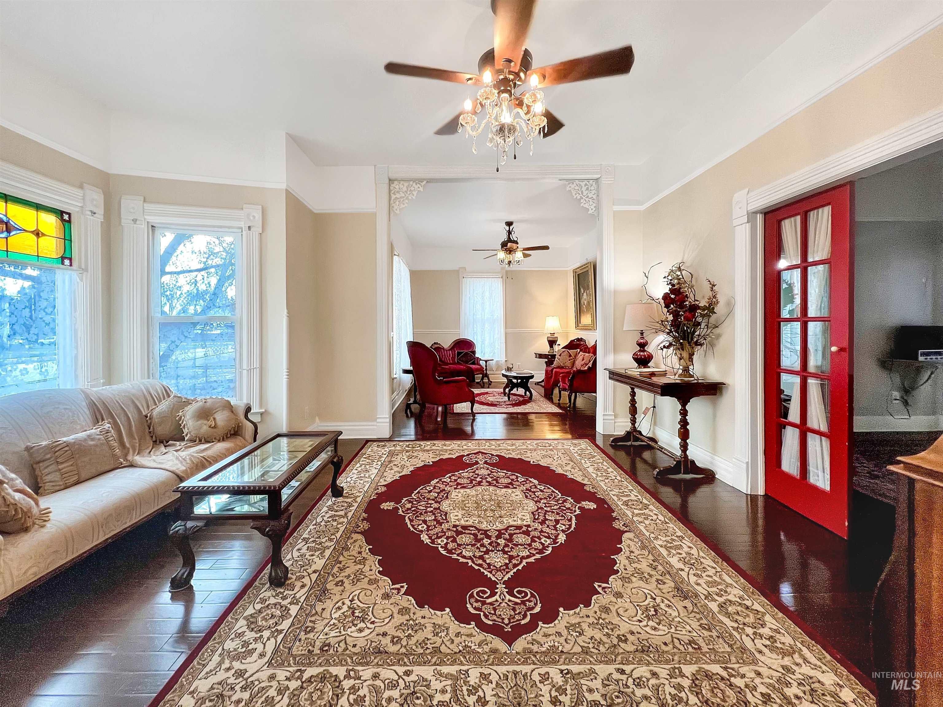 Living area featuring dark wood-style flooring, healthy amount of natural light, and ceiling fan