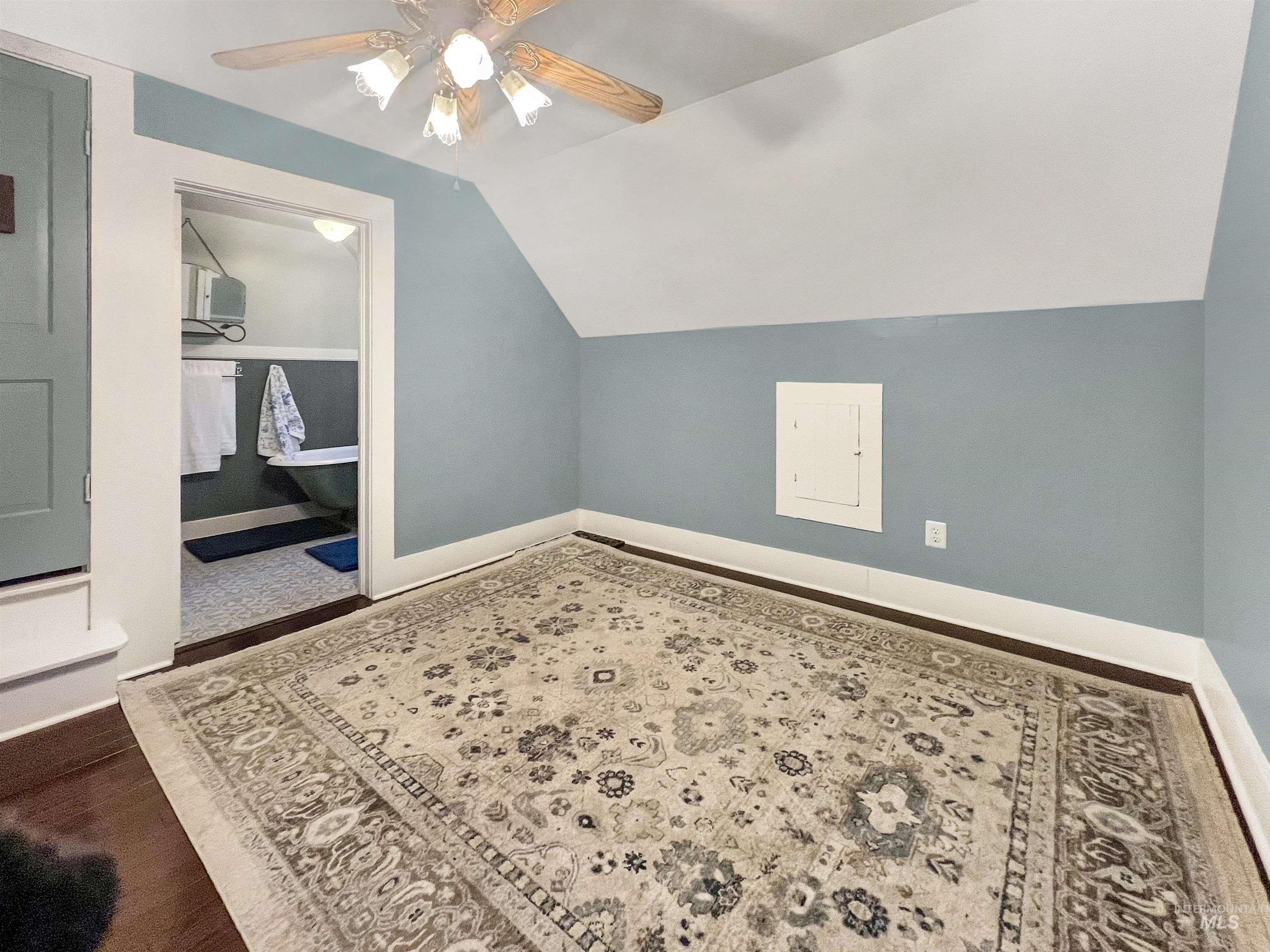 Additional upstairs bedroom featuring ceiling fan, vaulted ceiling, and dark wood-style floors