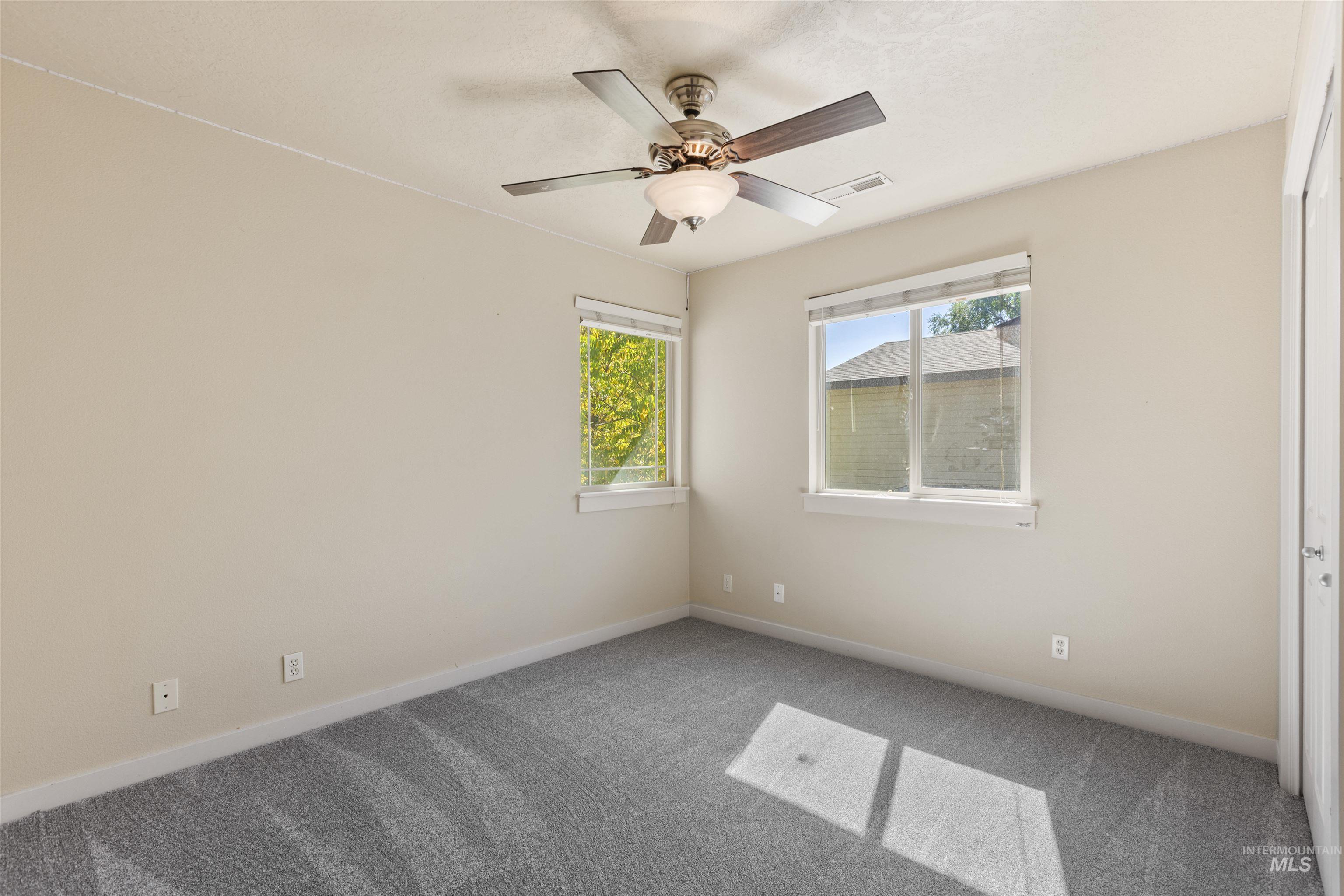 Carpeted empty room with baseboards and a ceiling fan