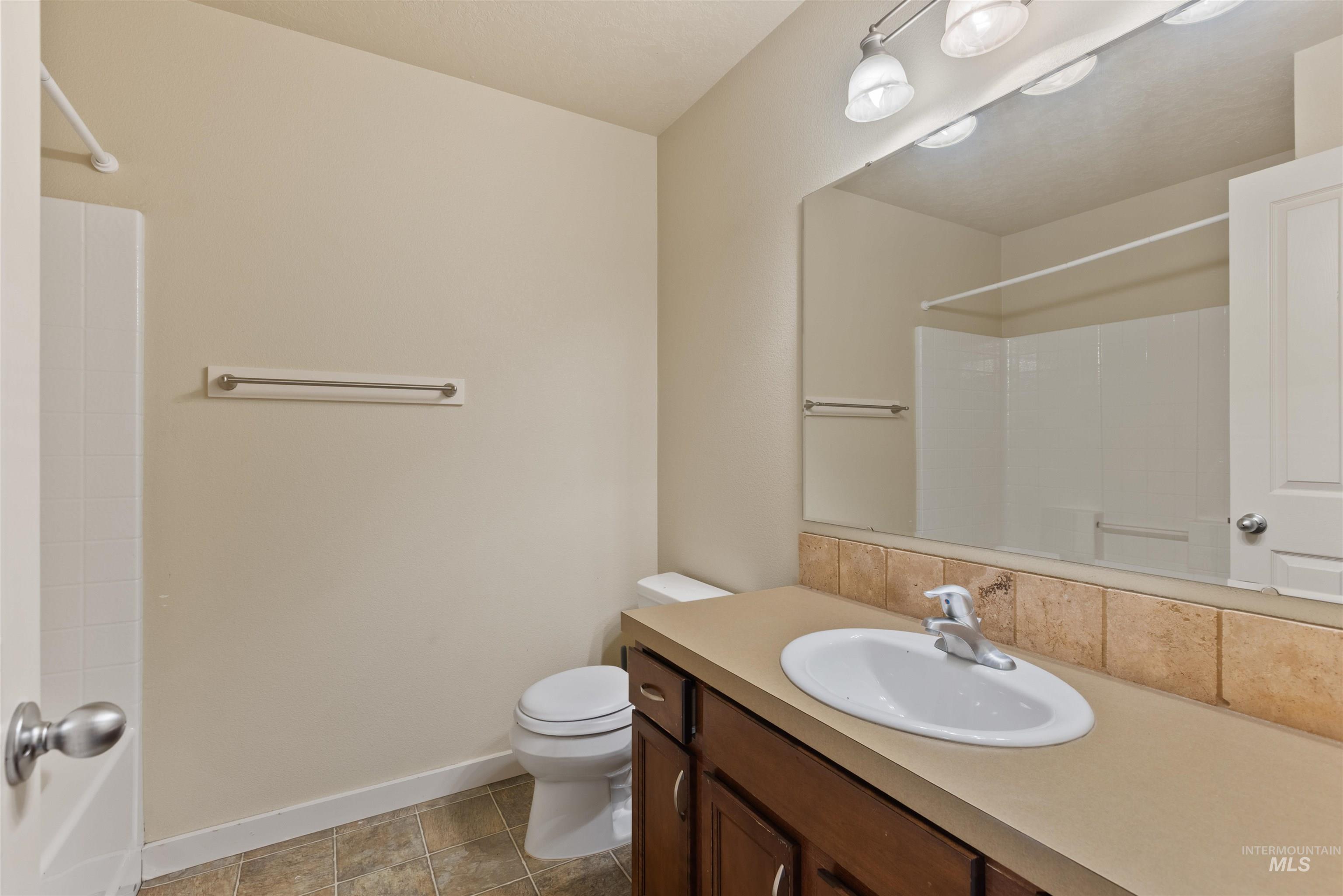 Full bathroom with vanity, light tile patterned floors, and backsplash
