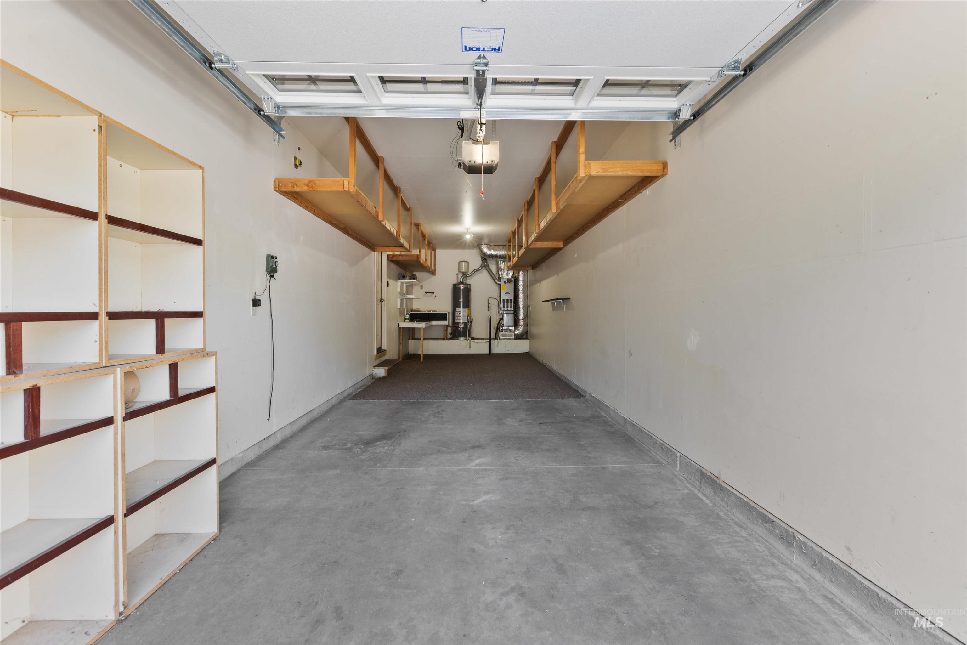 Garage with gas water heater, water heater, and a garage door opener