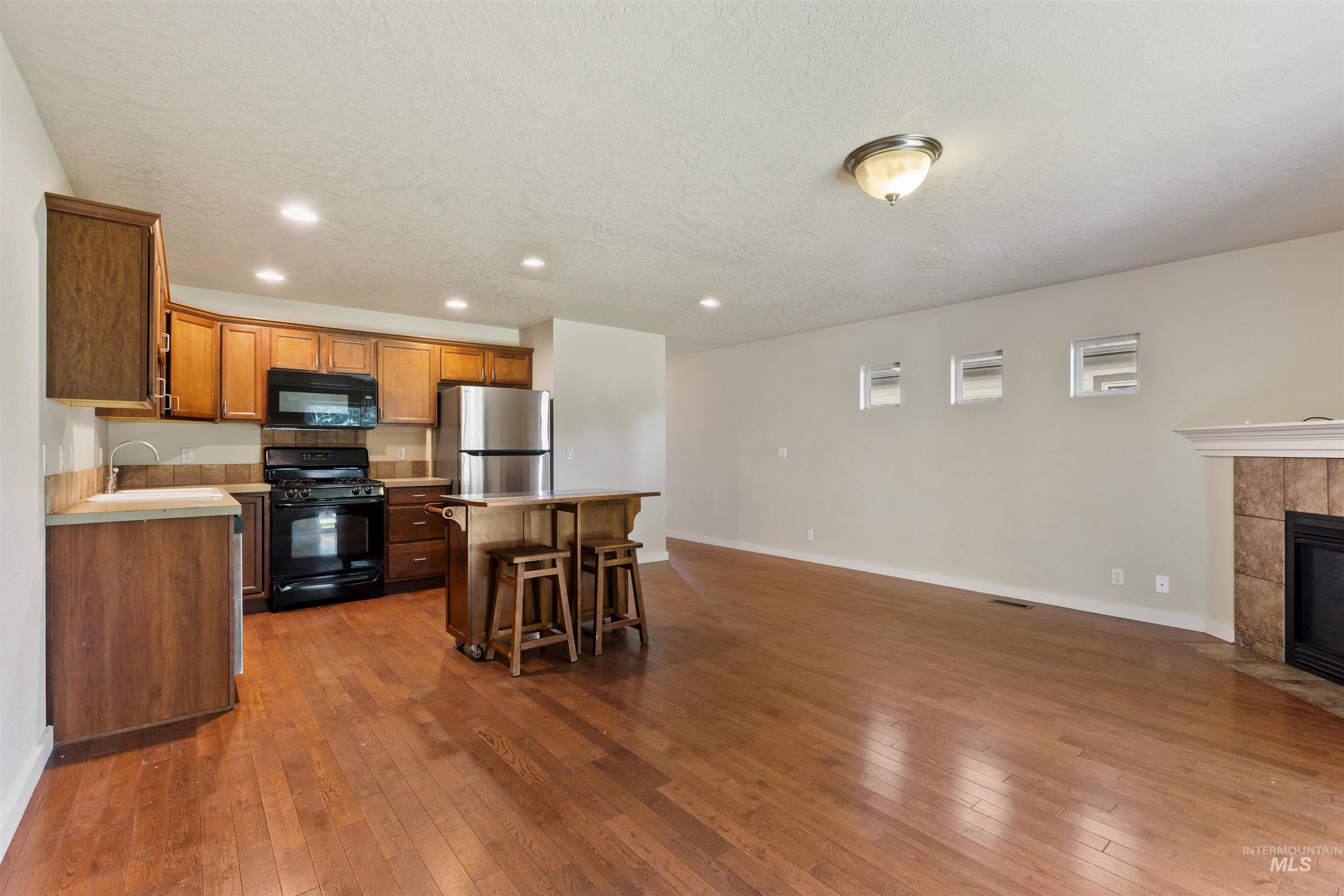 Kitchen with black appliances, light countertops, recessed lighting, a kitchen breakfast bar, and a center island