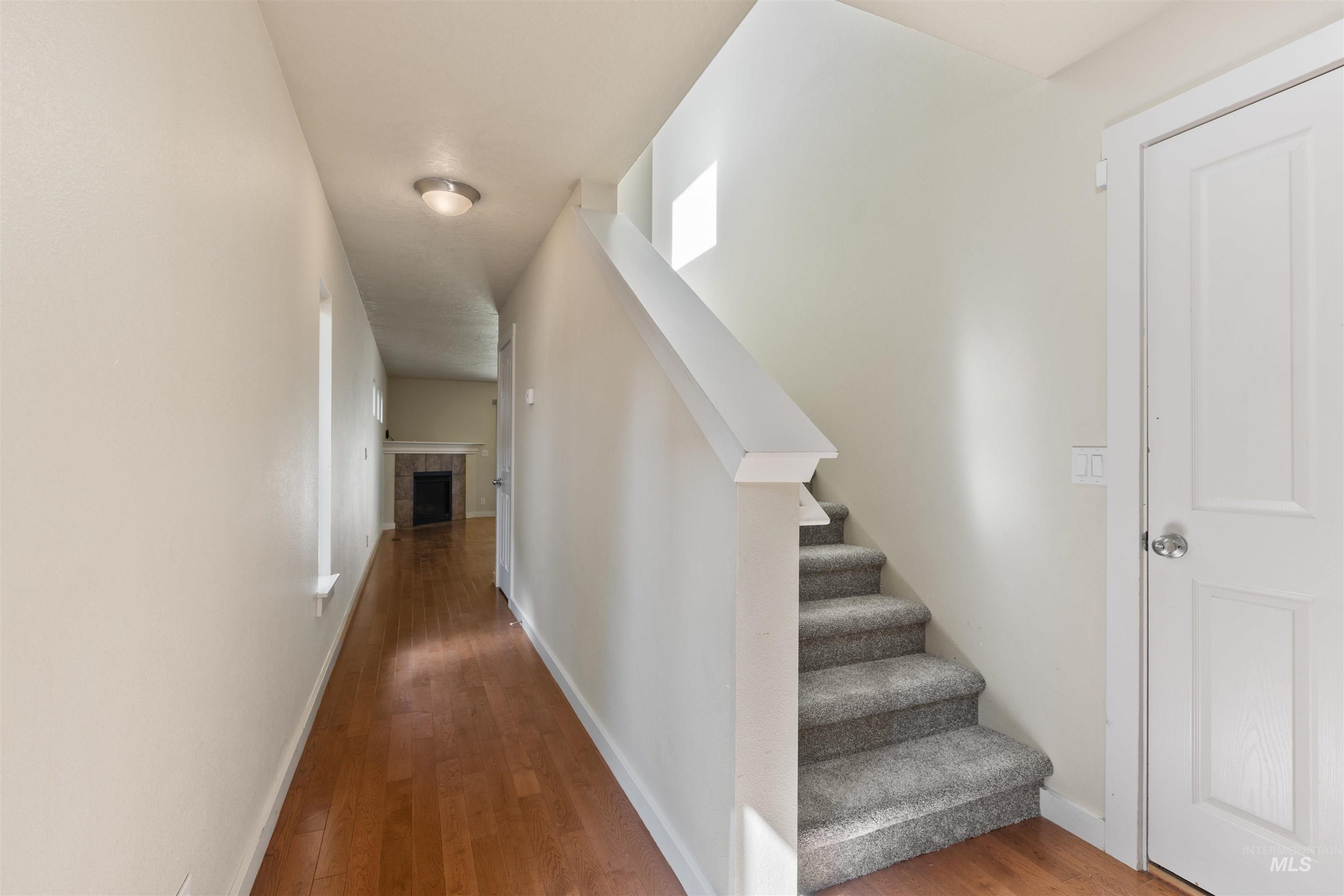 Hallway with wood finished floors and stairway