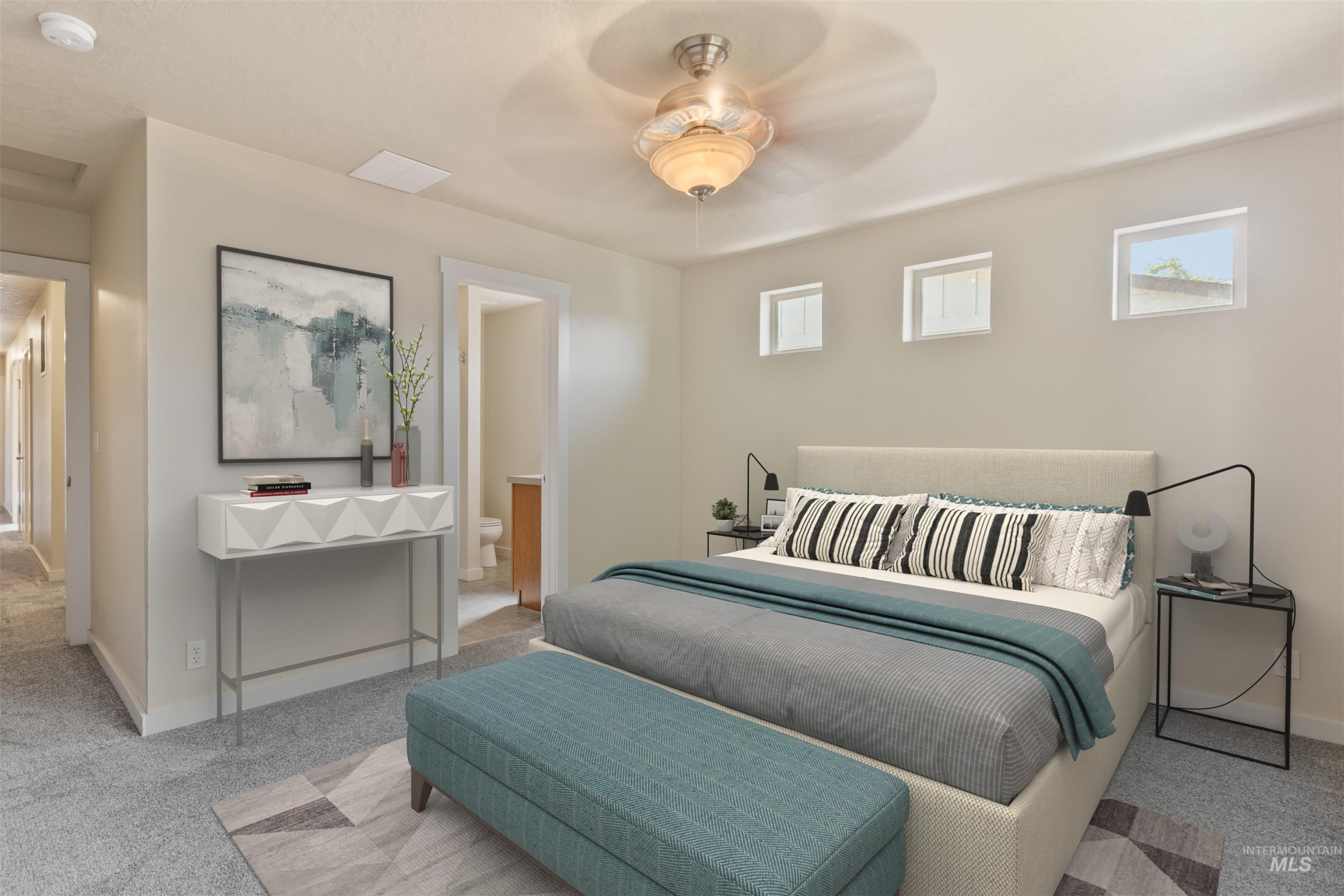 Bedroom with multiple windows, carpet flooring, ceiling fan, and ensuite bathroom